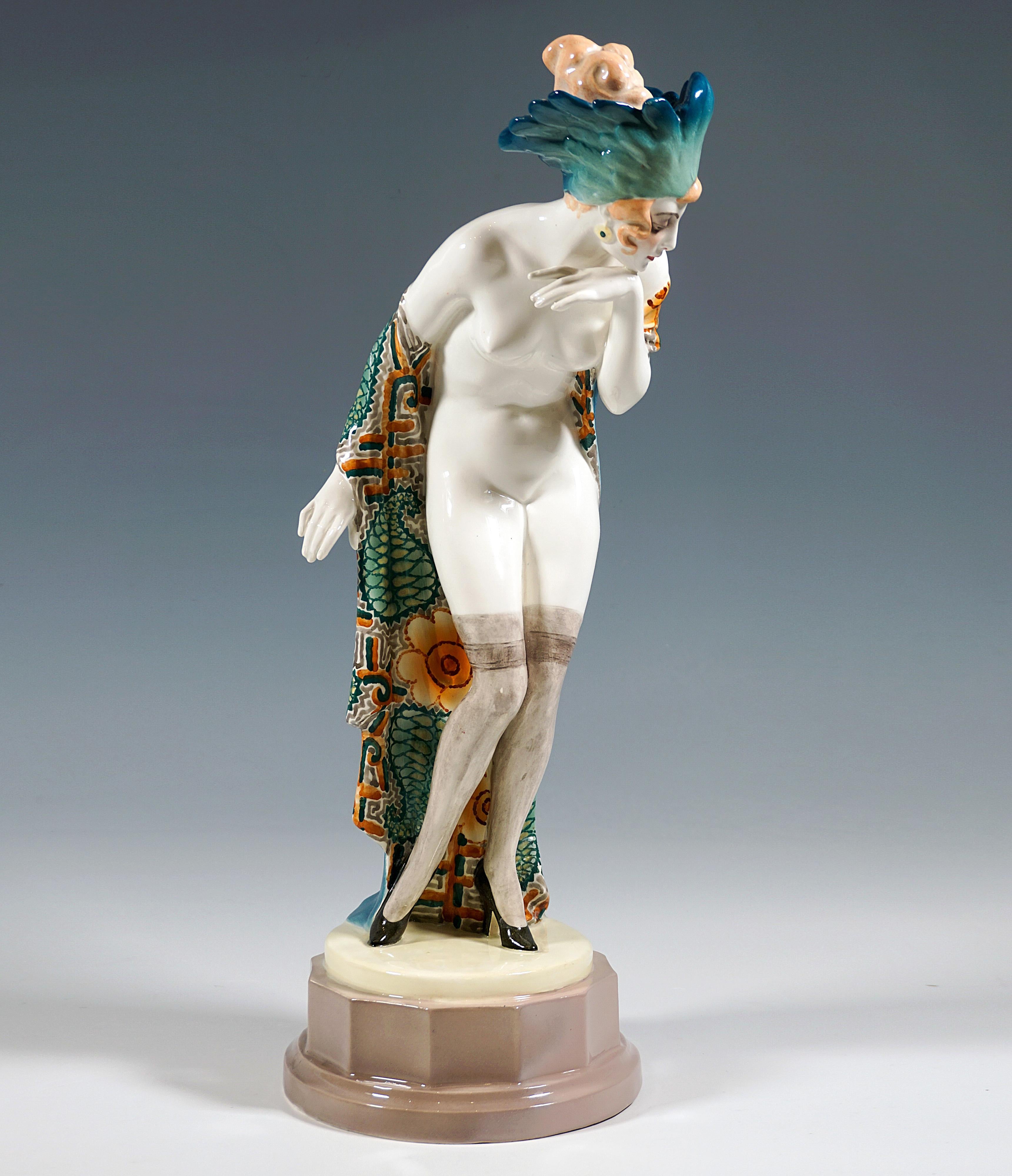 Impresionante figura de cerámica Goldscheider de Viena de los años veinte:
La joven, con el pelo artísticamente recogido, sólo lleva medias transparentes y zapatos de tacón alto, así como un tocado densamente decorado con plumas de tonos verde