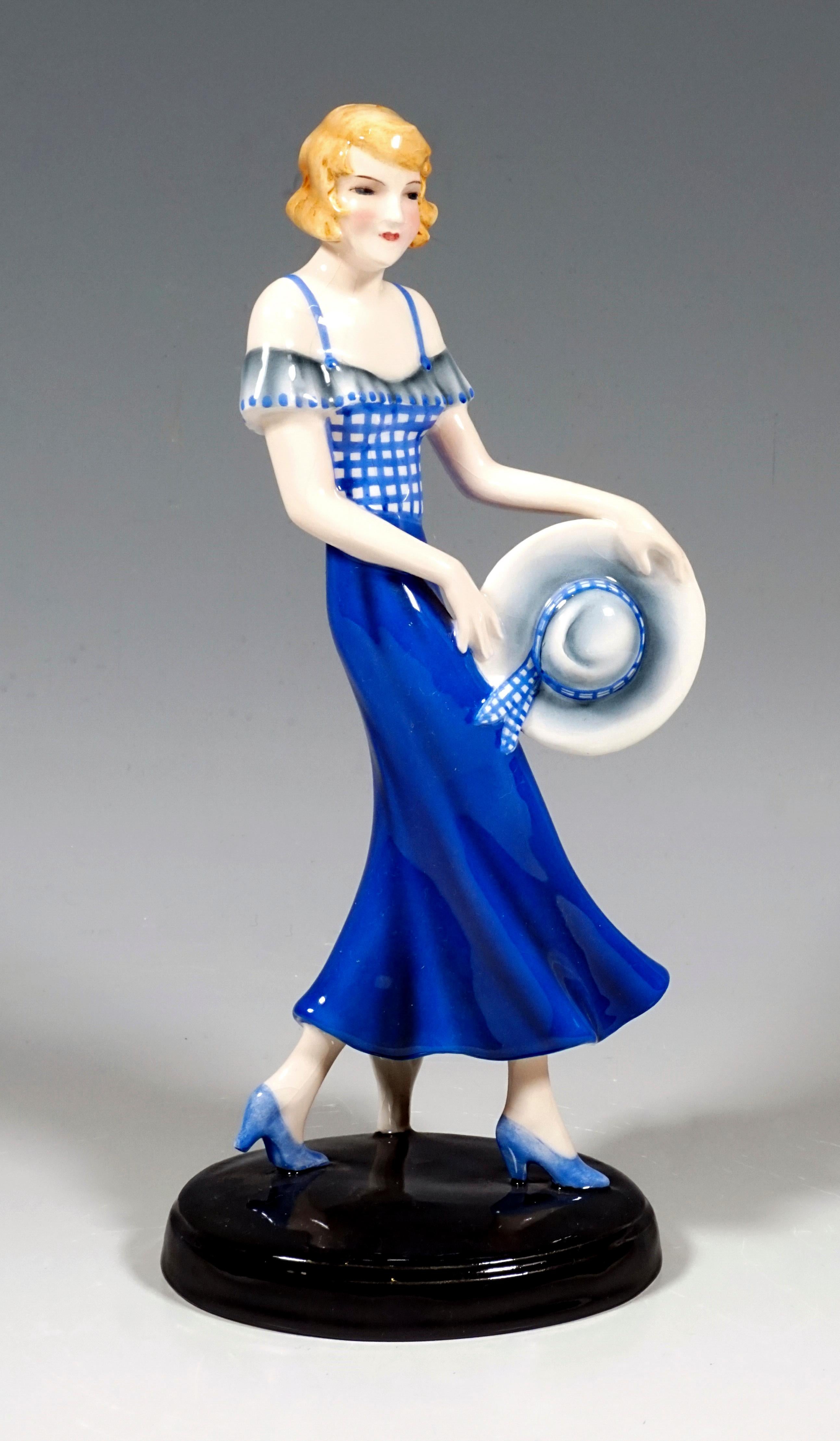 Very rare Goldscheider Vienna ceramic figurine of the 1930s:
The striding blonde girl in the blue pinafore dress holds her hat sideways in front of her. A gust of wind blows the bright blue skirt slightly forward. On a black oval base.

Signed