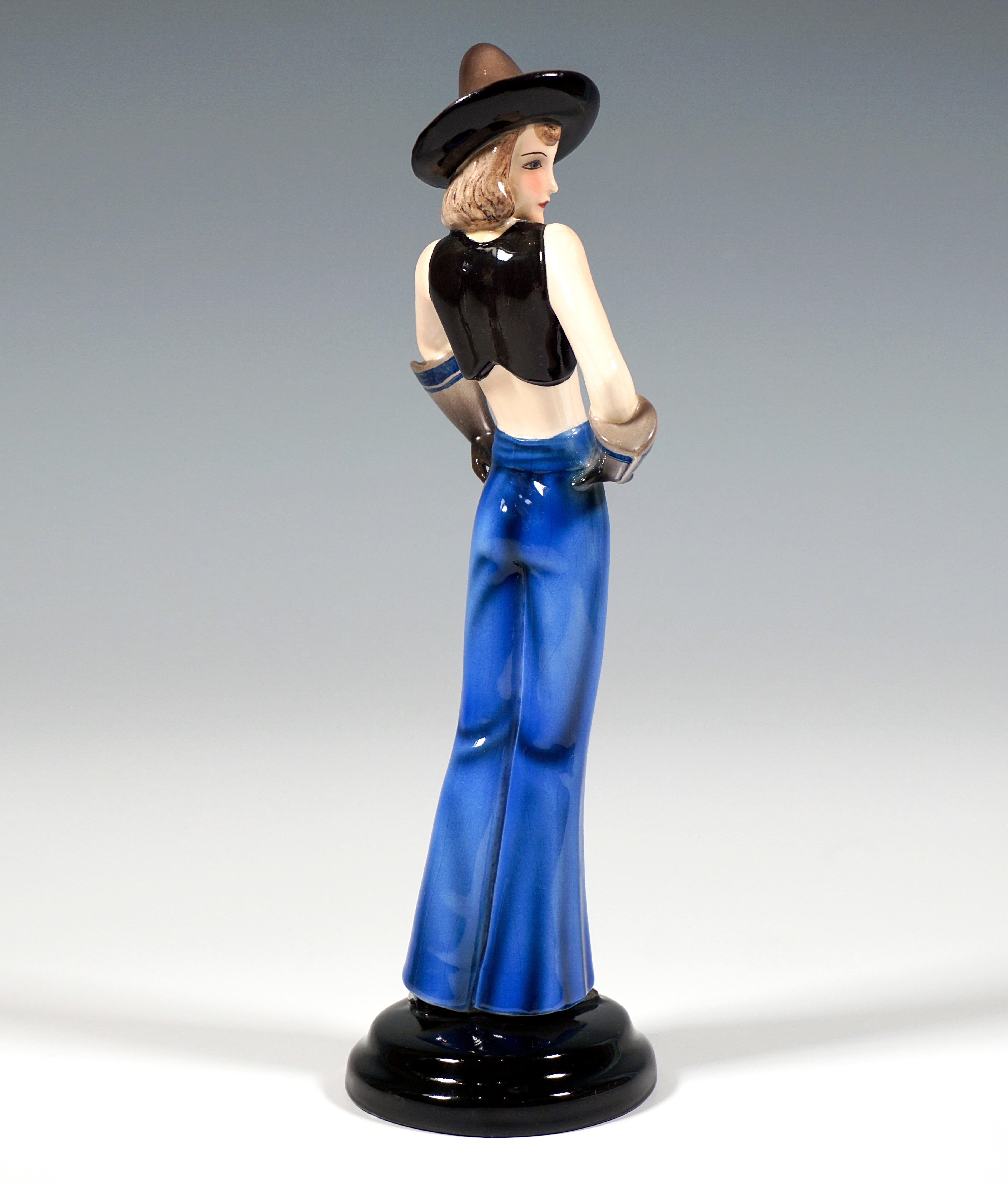 Very rare art ceramic figurine of the 1930s:
Standing girl with a pointed, sombrero-like hat on her chin-length brunette hair, dressed only in a black, short bolero jacket opened wide at the front and long blue flared pants and pointed shoes on her