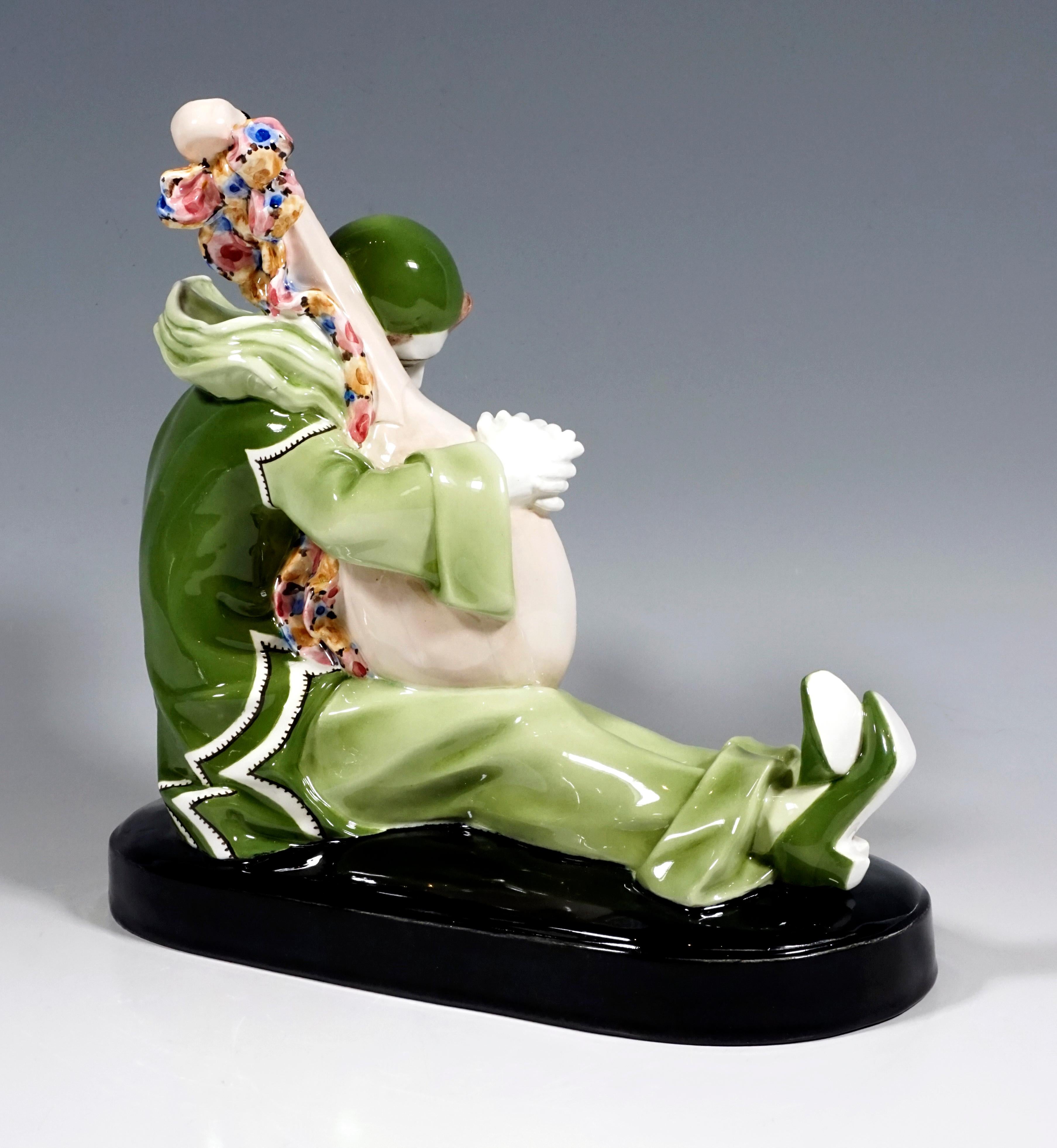 Depicted is a young musician, dressed up as Pierrot, who is sitting on the elongated base with his legs outstretched and hugging his lute. He wears a green suit with a wide, multi-layered collar, hood, long trousers and high heel shoes.
On a black