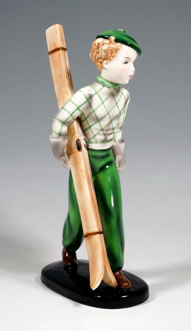 Very rare Goldscheider Vienna figurine of the 1930s.
Striding, blond-haired boy in green-colored ski clothing from the 1930s, carrying his wooden skis under his arm.
On a black oval base.

Designed by Stefan Dakon (1904-1992), one of the most