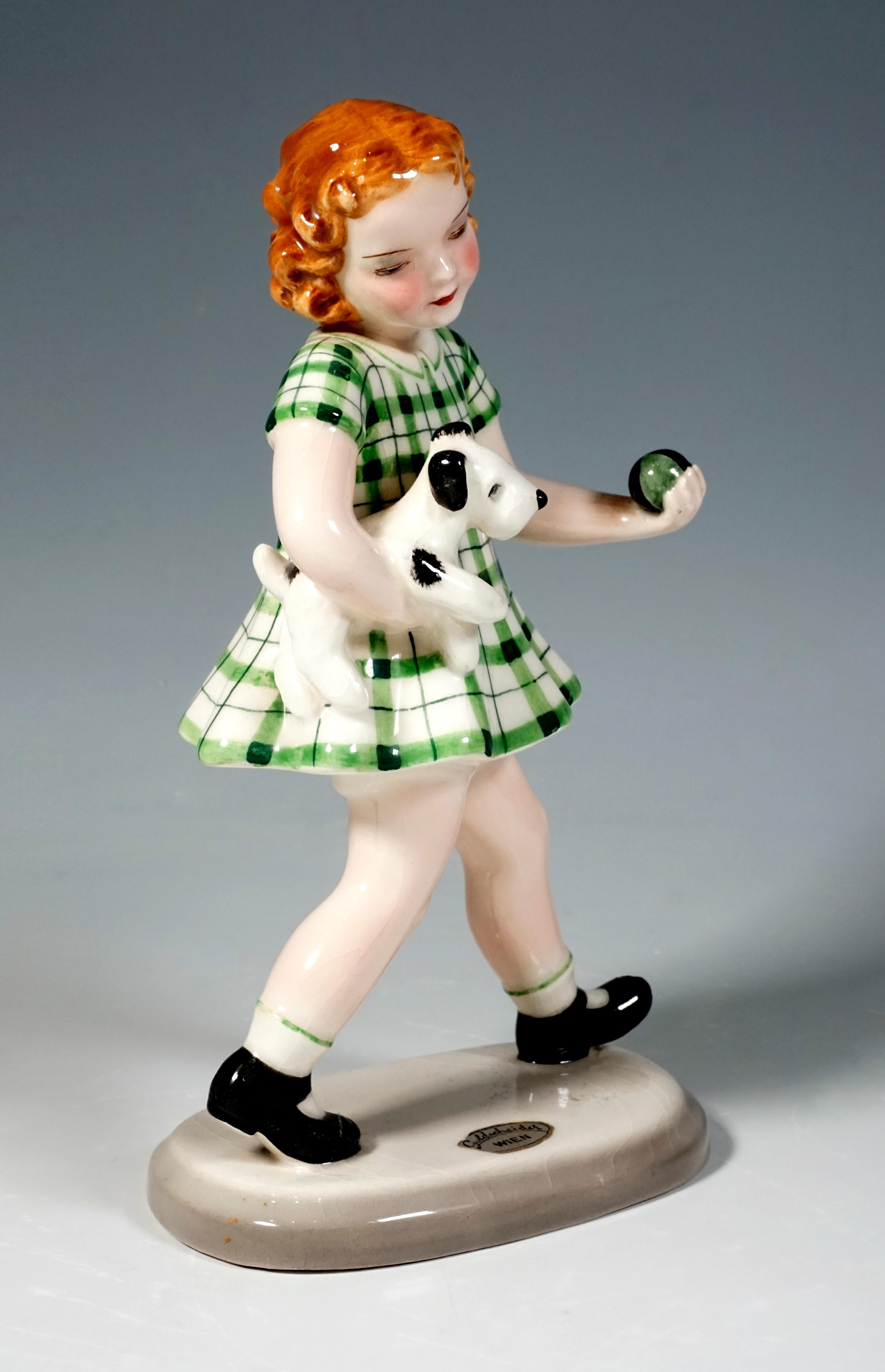 The striding red-haired girl in a green checkered dress carries a small dog under her right arm, in her left hand she holds a small green-black ball.
On a beige, oval base.

Designed by Adolf Prischl (1912 - 1970), Sculptor, numerous of his