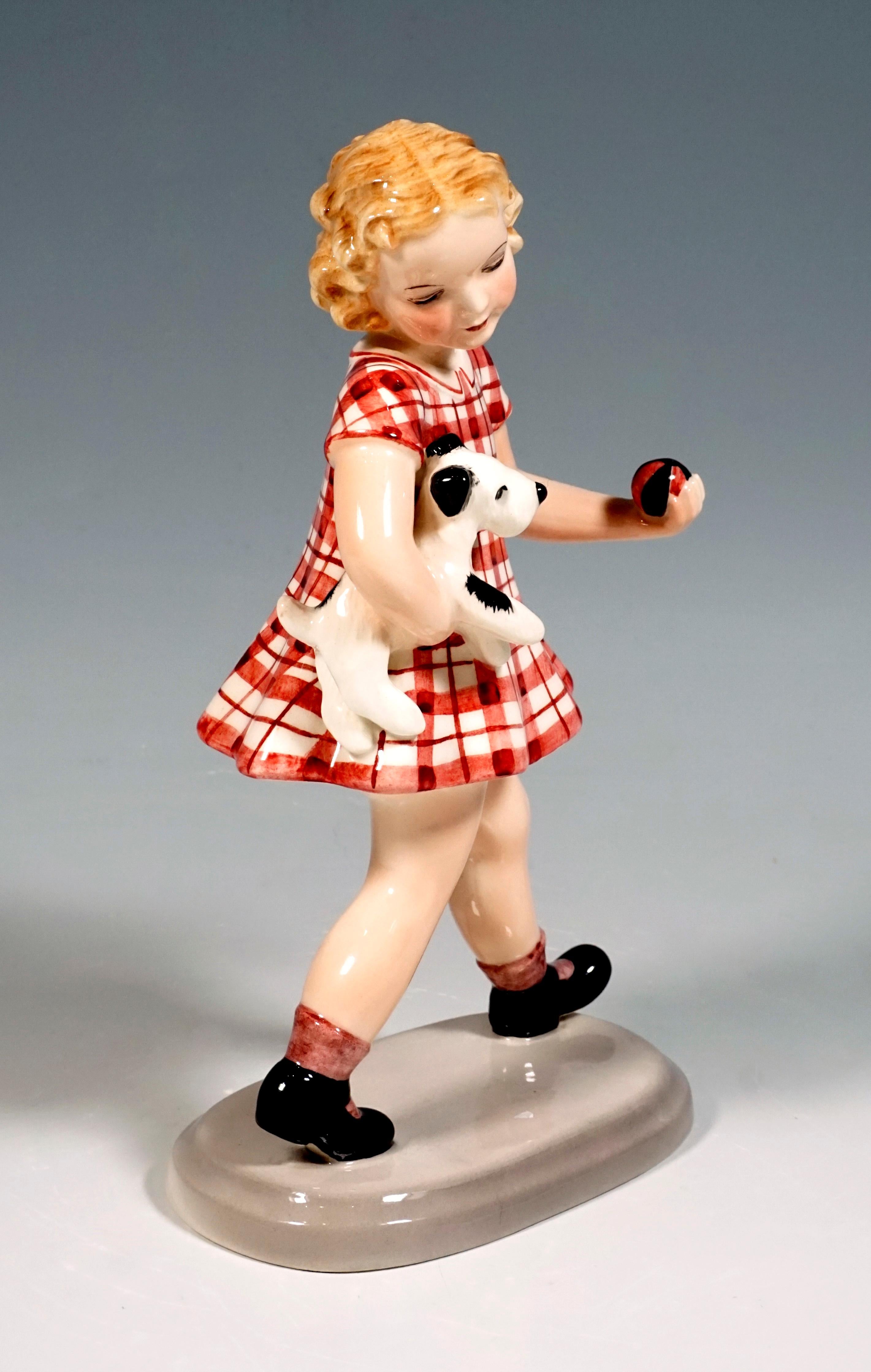 The striding blonde-haired girl in a red checkered dress carries a small dog under her right arm, in her left hand she holds a small red-black ball.
On a beige, oval base.

Designed by Adolf Prischl (1912 - 1970), Sculptor, numerous of his models