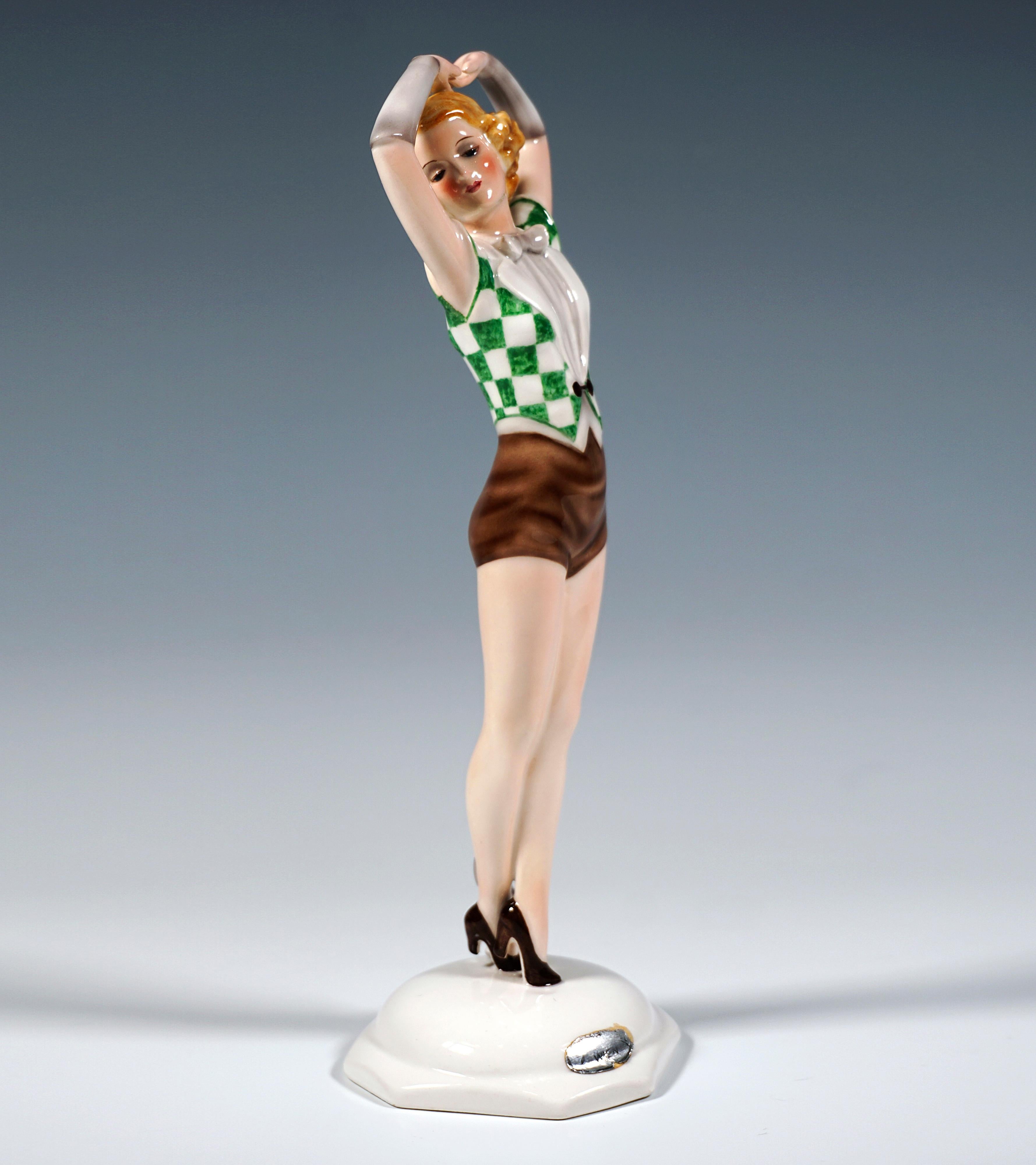 Sehr seltene und außergewöhnliche Goldscheider Wien Keramik Figur aus den 1930er Jahren:
Eine junge Tänzerin mit kinnlangem, lockigem, blondem Haar, die auf den Spitzen ihrer Absätze steht, kurze braune Hosen und eine grün-weiß karierte ärmellose