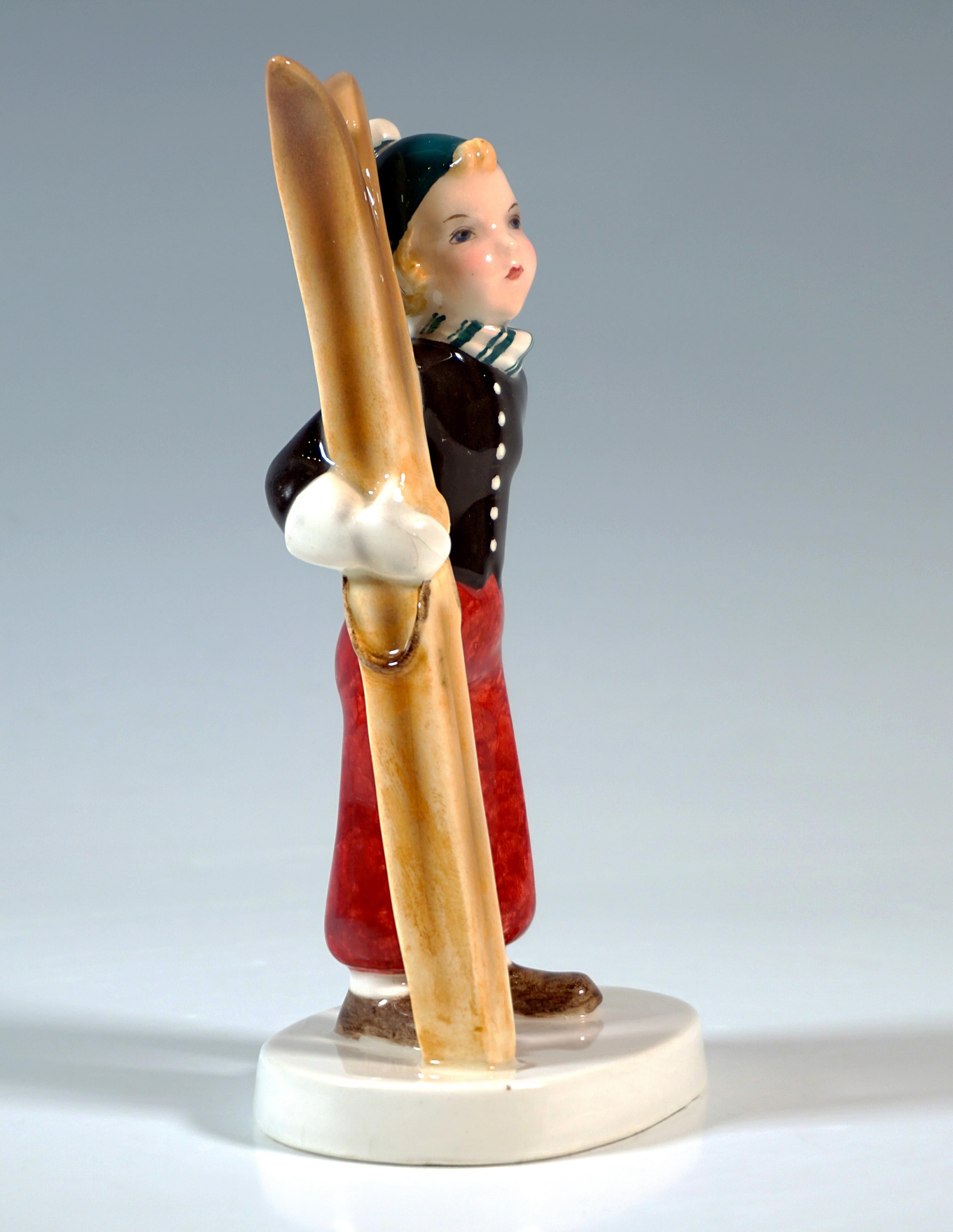 Rare figurine Goldscheider Vienna des années 1930 :
Une jeune fille debout en tenue de ski des années 1930 - bonnet pointu, gilet chaud, écharpe, pantalon de ski large, chaussures robustes, moufles épaisses, tenant des skis en bois, l'autre main