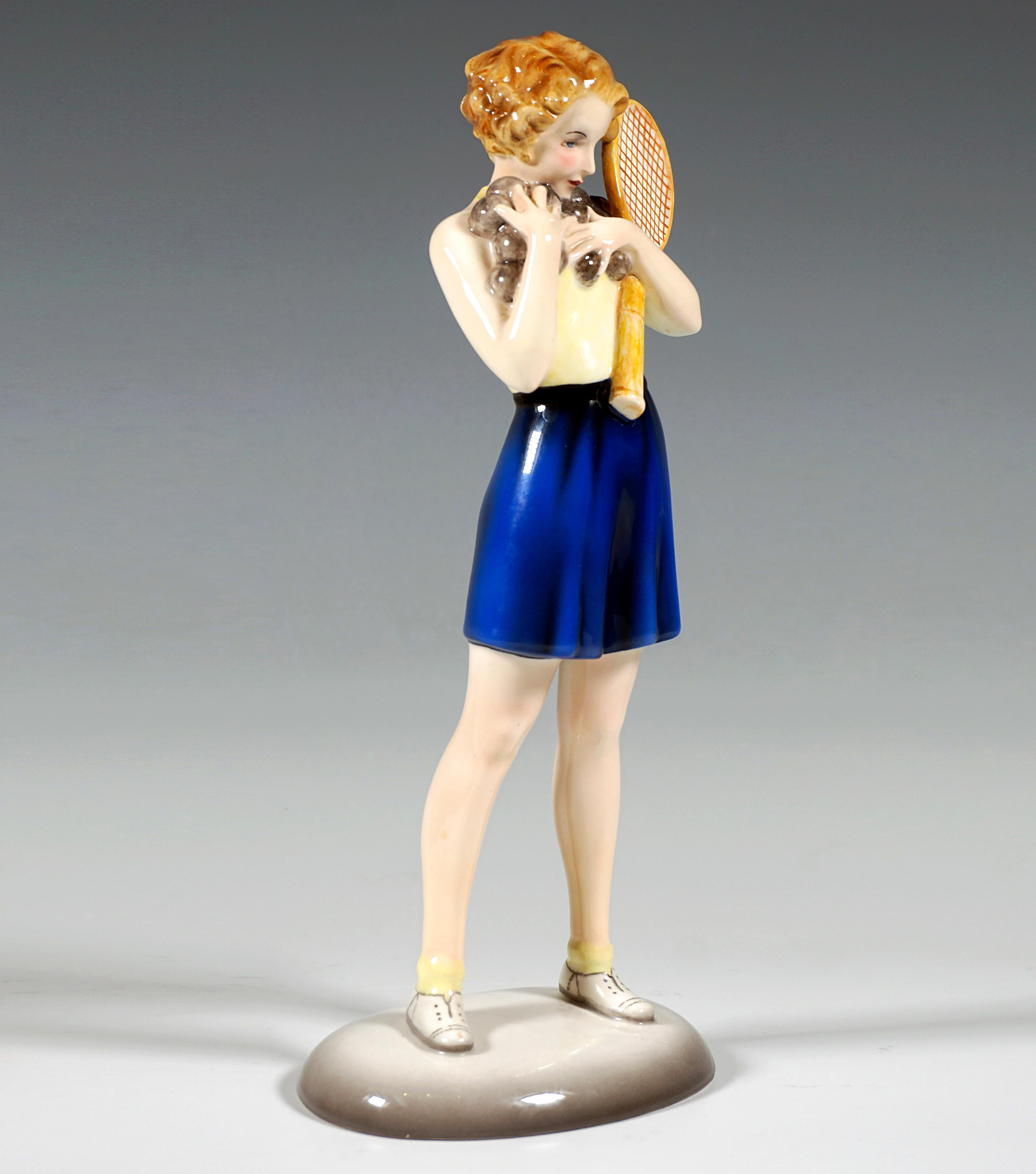 Very Rare Goldscheider Vienna Ceramic Figurine of the 1930s:
Young girl in tennis clothes: backless light-colored top, dark blue, wide, short pants and white tennis shoes, standing with her legs apart, holding a multitude of tennis balls with both