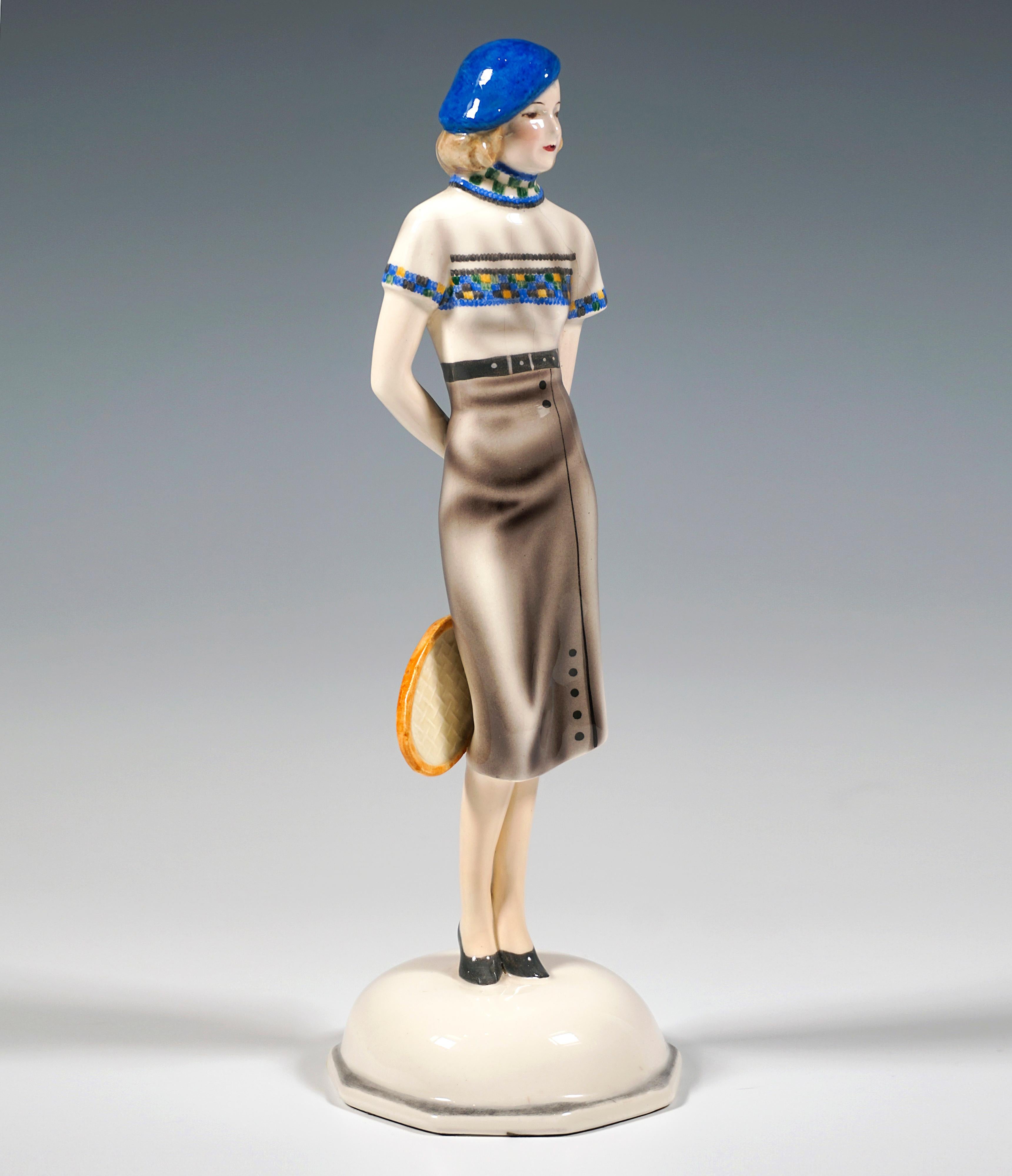 Very Rare Goldscheider Vienna Ceramic Figurine of the 1930s:
Standing elegant young lady with a blue beret cap on her chin-length blond hair, wearing a patterned short-sleeved sweater and a long, tight skirt, holding a tennis racket with her left
