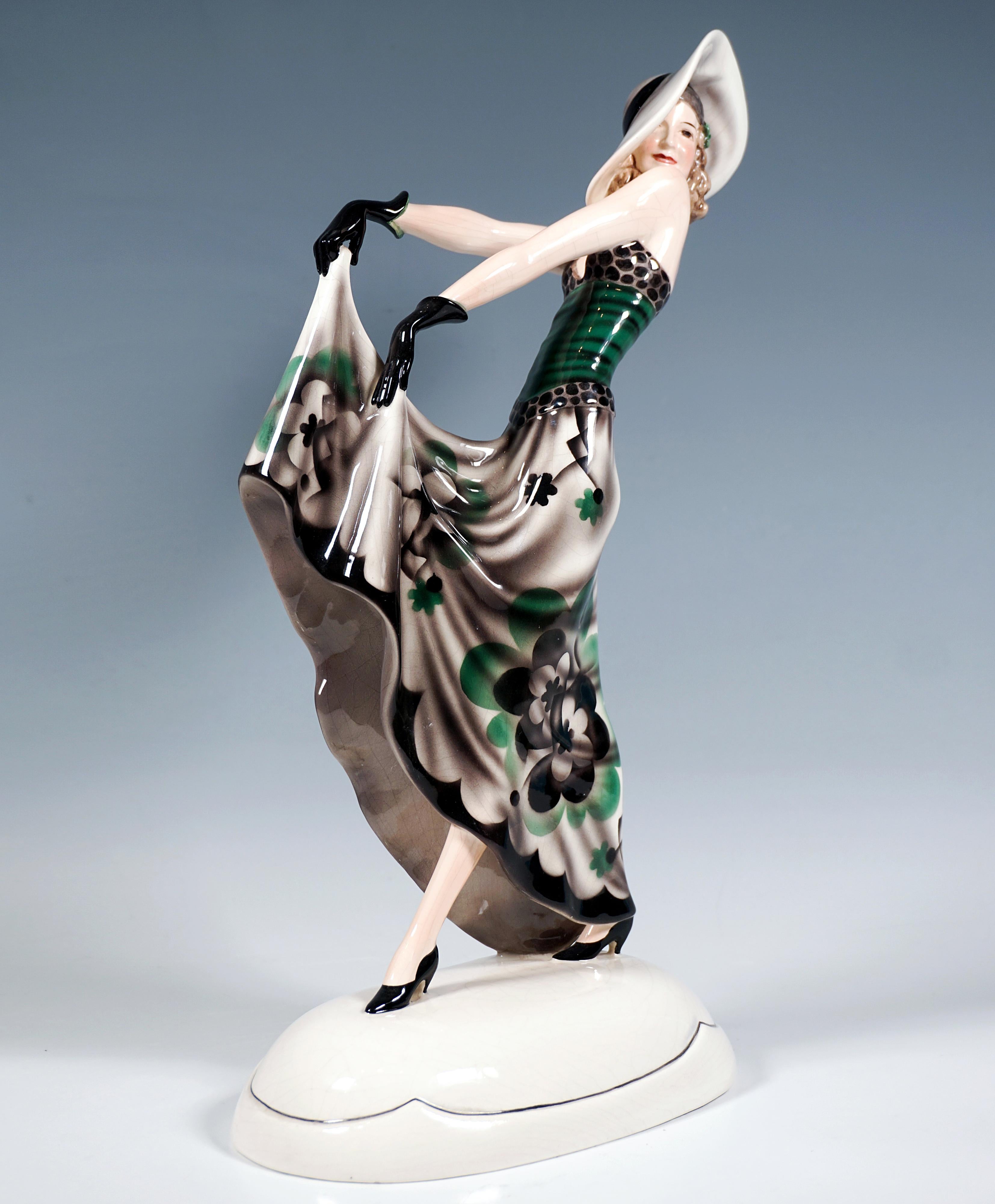 Finest Viennese Art Ceramic from the 1930s:
Actress Lilian Harvey as a walking lady with a large hat, wearing a tight-fitting emerald green top with a bustier dotted black on light grey, lifting the hem of her long skirt with a large abstract floral