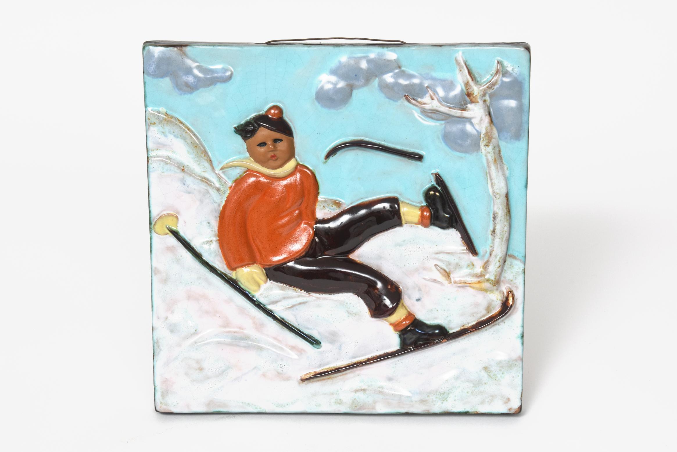 Goldscheider pottery plaque depicting in relief a falling skier boy with his ski breaking and flying off The young man is passing a tree while skiing down the mountain on the snow.

Marked Goldscheider Wien made in Austria 8238 over 65.