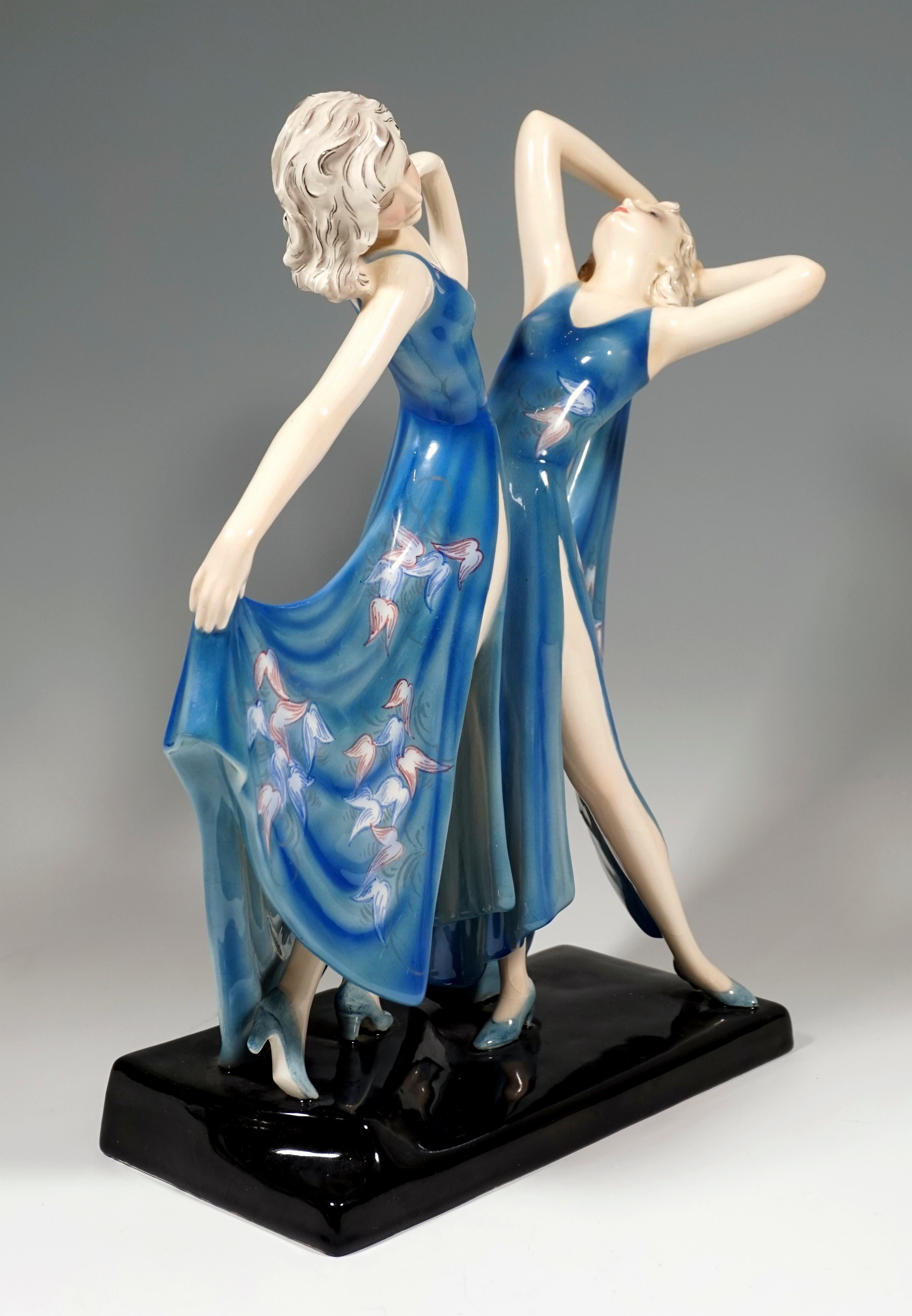 Rare Viennese ceramic Art from the 1930s:
Two graceful dancers in long, deeply cut and high slit blue dresses with floral decorations, facing each other with their upper bodies leaning back and holding the skirt ends performing a dance pose.
On a