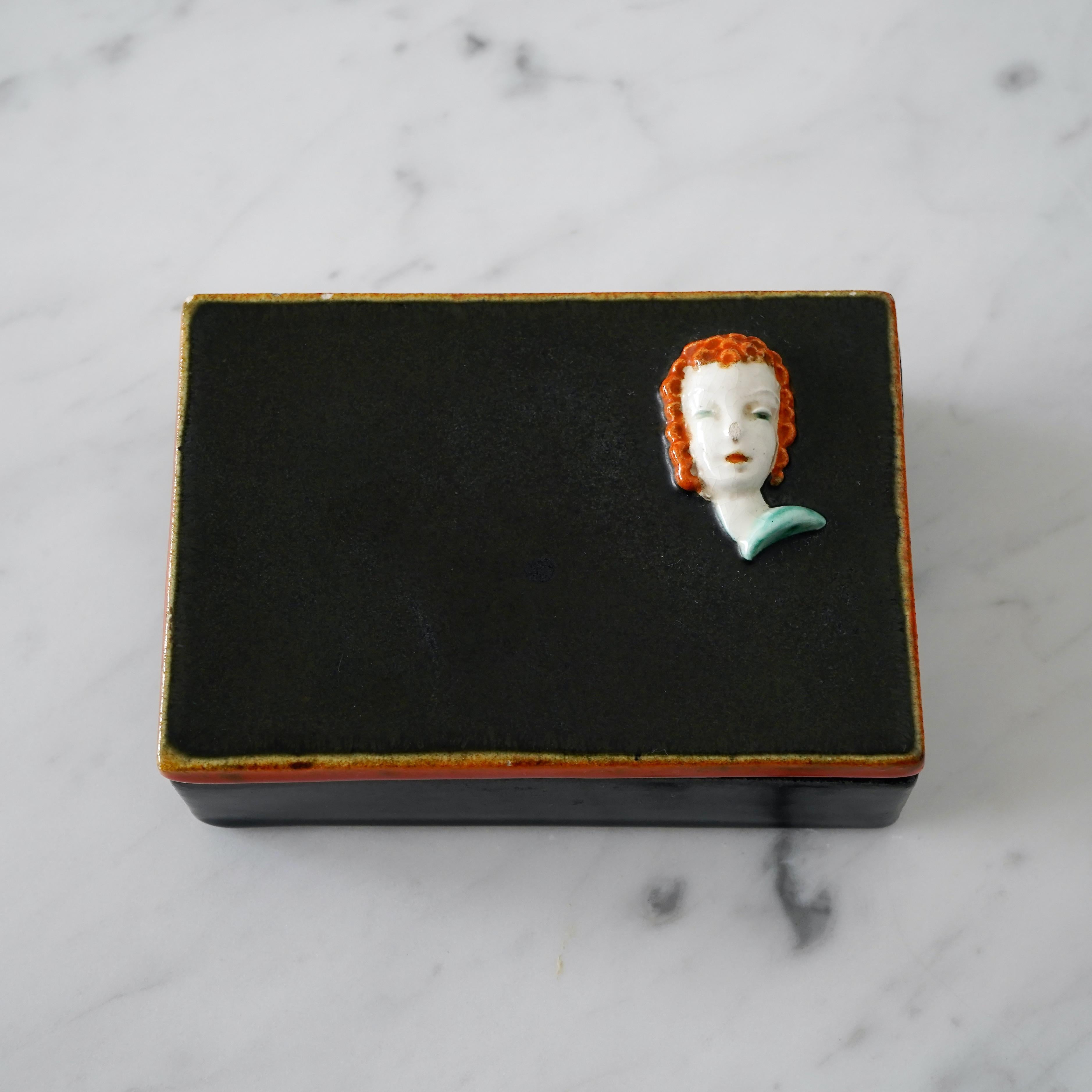 Una caja con tapa art decó muy rara y hermosa. Esmaltado y pintado a mano con un asombroso retrato de una mujer con el pelo rizado.

Diseñado por Rudolf Knörlein para Friedrich Goldscheider, Viena, Austria, 1930-1936.

Buen estado vintage, con un