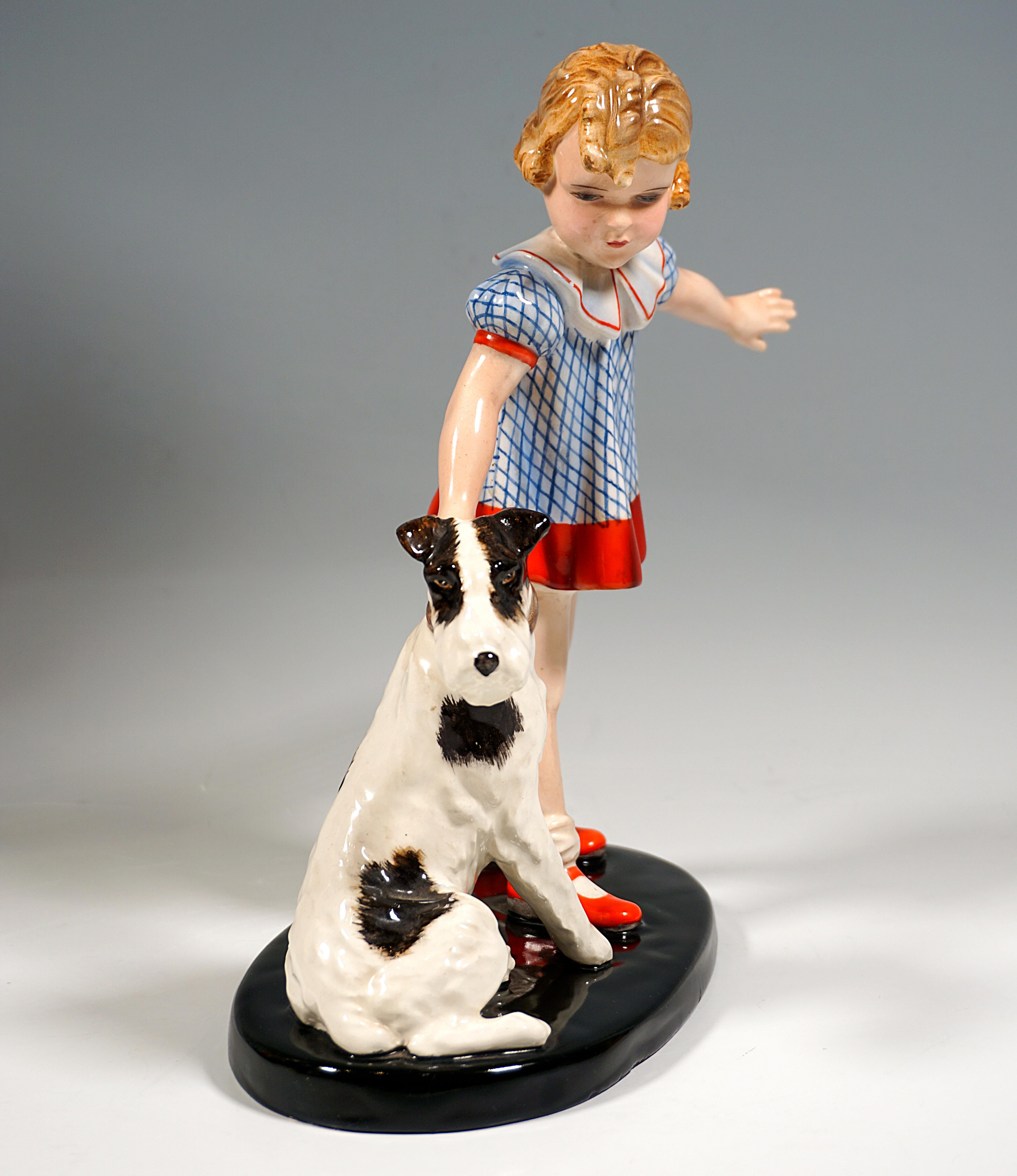 Rare Goldscheider Vienna Art Déco Art Ceramic Group of the late 1930s:
Little blond girl with curly hair in a white and blue checked summer dress with red edges holding a fox terrier sitting on the ground next to her by the collar and pulling on