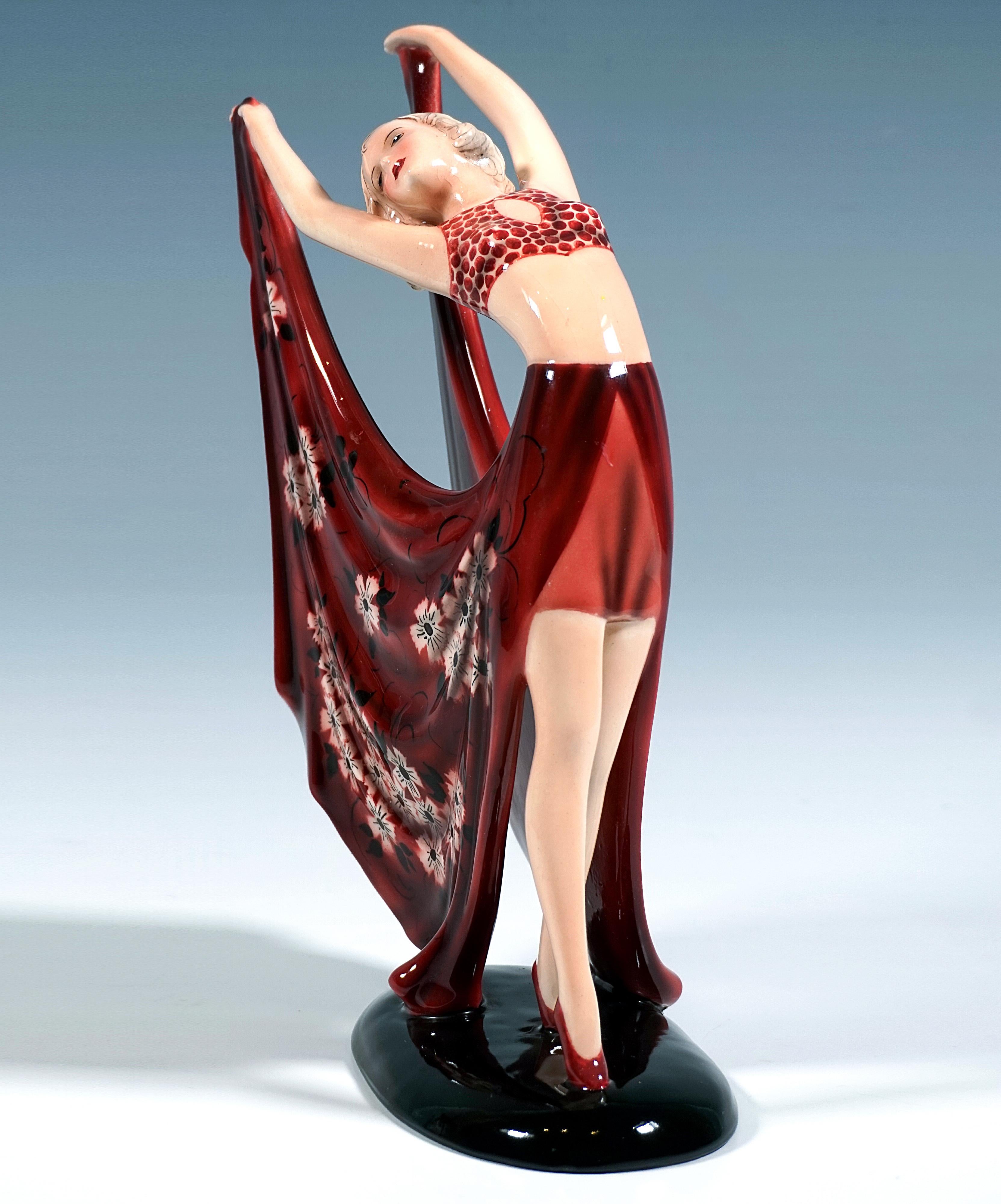 Delicata statuetta in ceramica Art Déco Goldscheider della fine degli anni '30:
Ballerina in posa aggraziata in costume rosso scuro: bustier a pois e gonna corta sul davanti con lunghi e ampi pannelli laterali a spacco sul retro con decorazioni