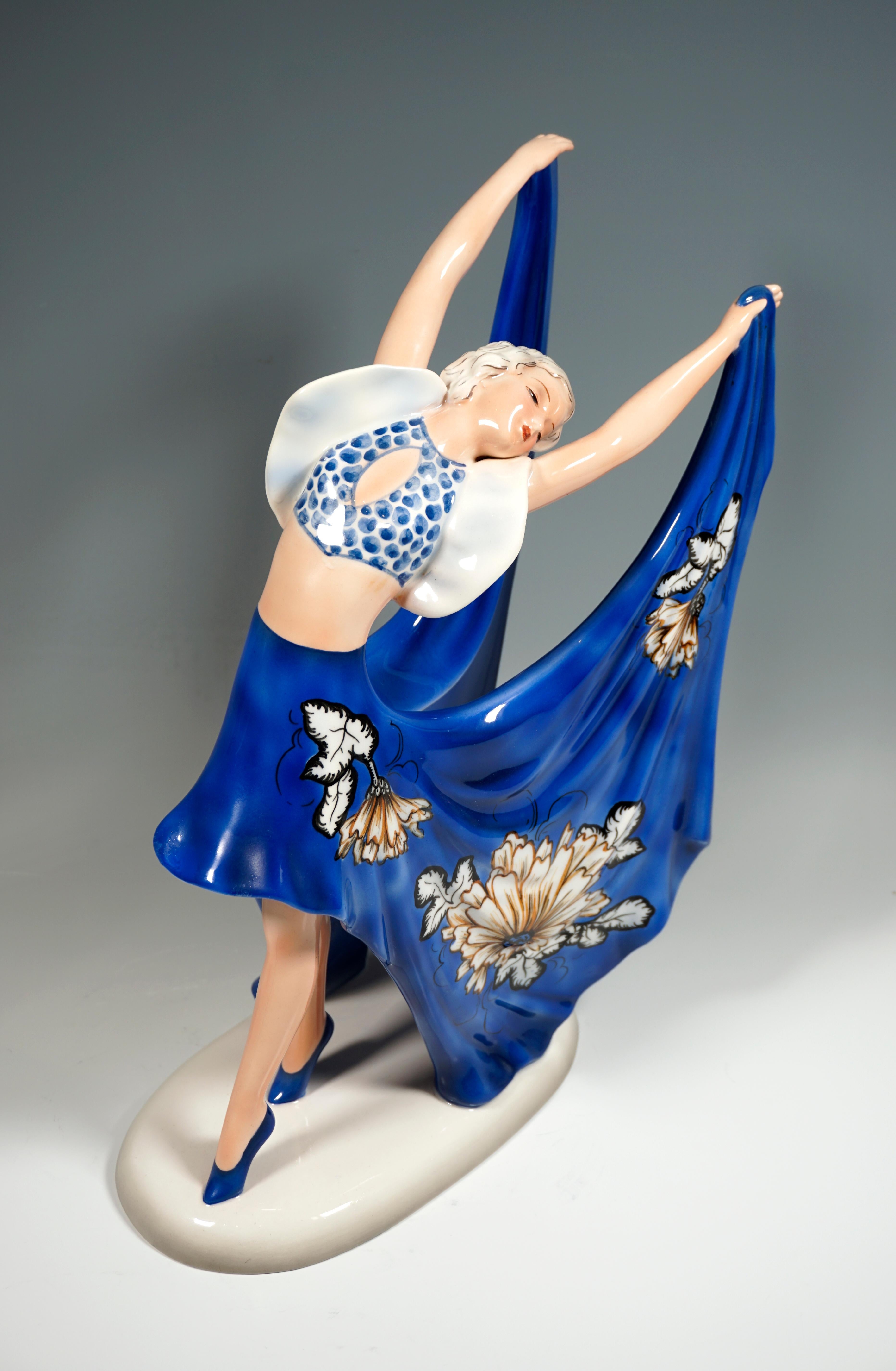 Rare Goldscheider Art Déco Ceramic Figurine.
Gracefully posing dancer in blue and white costume: dotted bustier with white cap sleeves and a short skirt at the front with long, wide side parts slit on the back with white, yellow and black floral