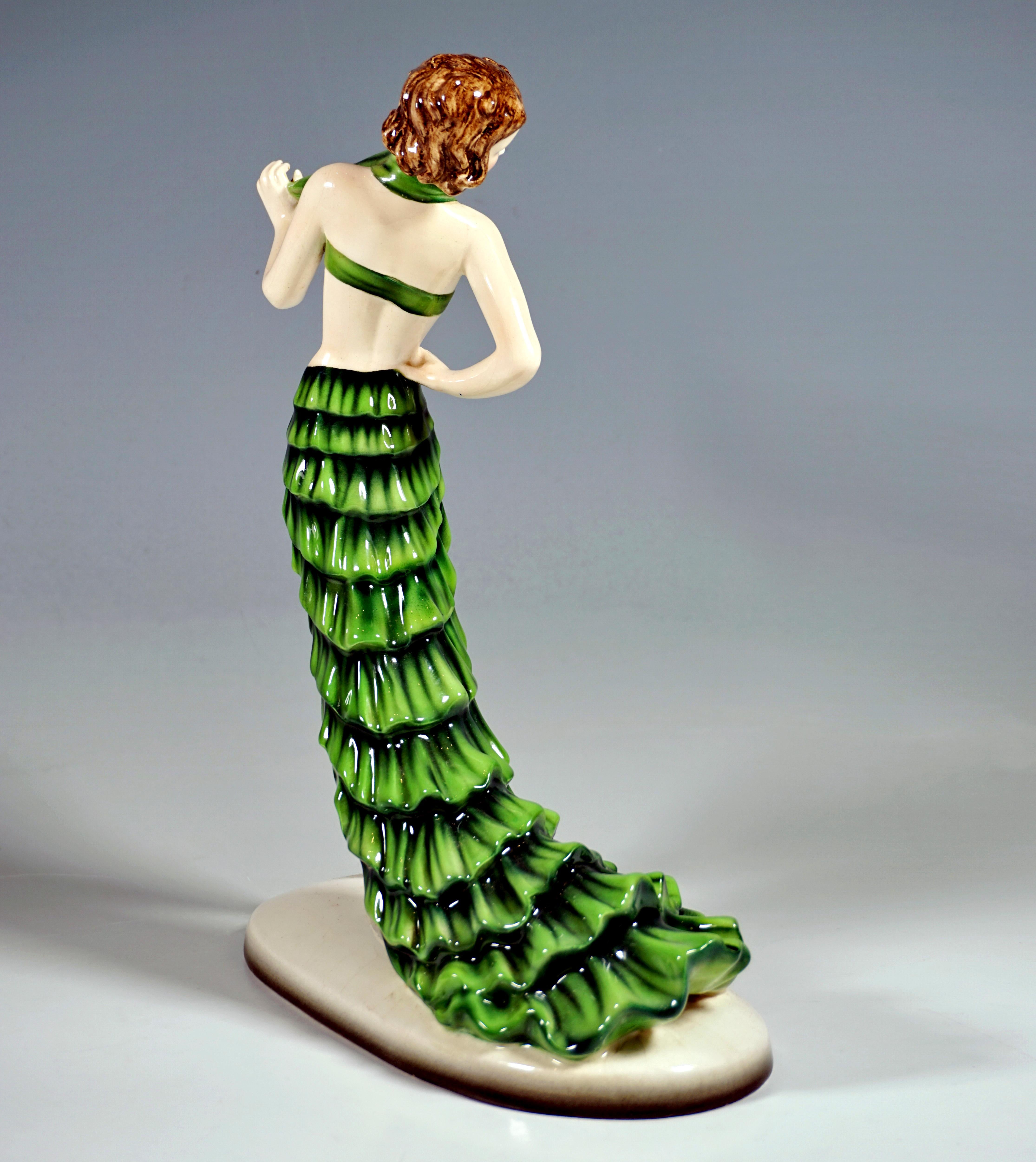 Rare Goldscheider Art Déco Ceramic Figurine of the 1930s:
Posing dancer with short hair in a green costume: tight bustier and a short, high-slit flounced skirt with a long train and matching high-heeled shoes, the right leg placed in front, the