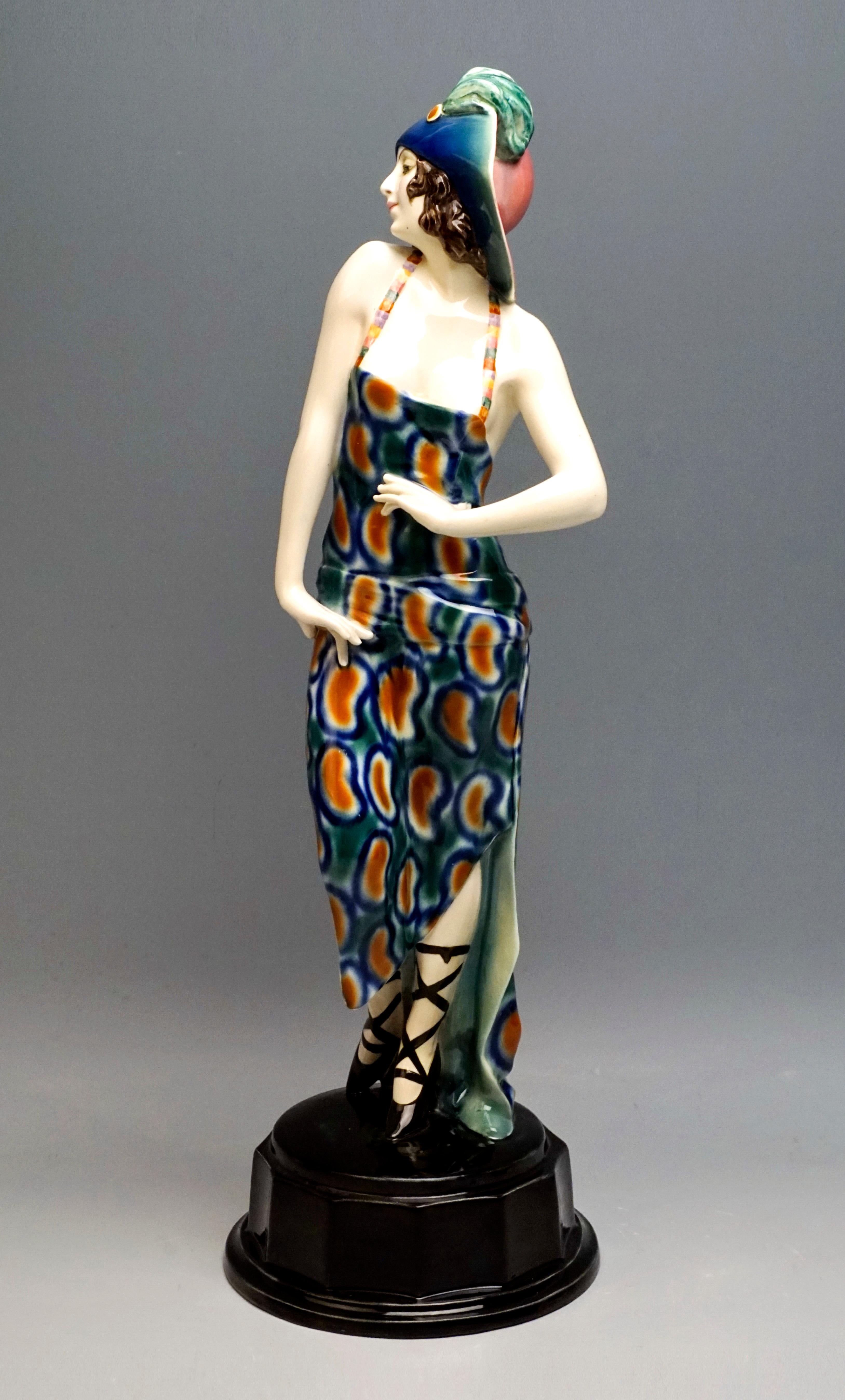 Very rare Goldscheider ceramics figure of the 1920s.
The dancer wears a red hat, the broad brim, colored on the inside from blue to green, is folded up at the front and fastened with a pin adorned with feathers. Her asymmetrical pinafore dress in