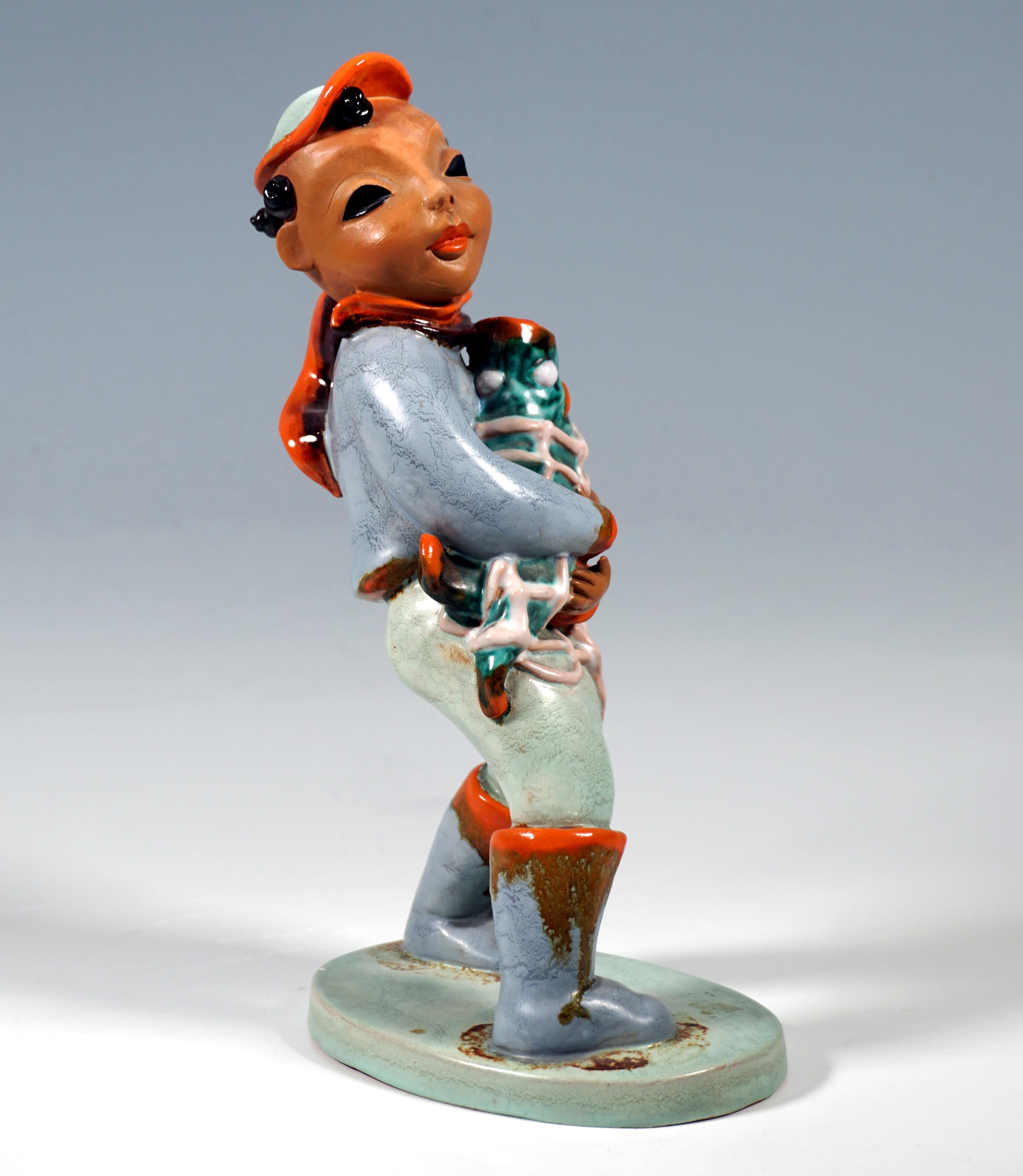 Very Rare Goldscheider Art Déco figure of the 1930s:
Boy with cap, scarf and boots holding a big fish in the net in his arms.
On a flat oval base, red ceramic, glazed in shades of green & blue, white, red and brown.

Designed by Kurt GOEBEL