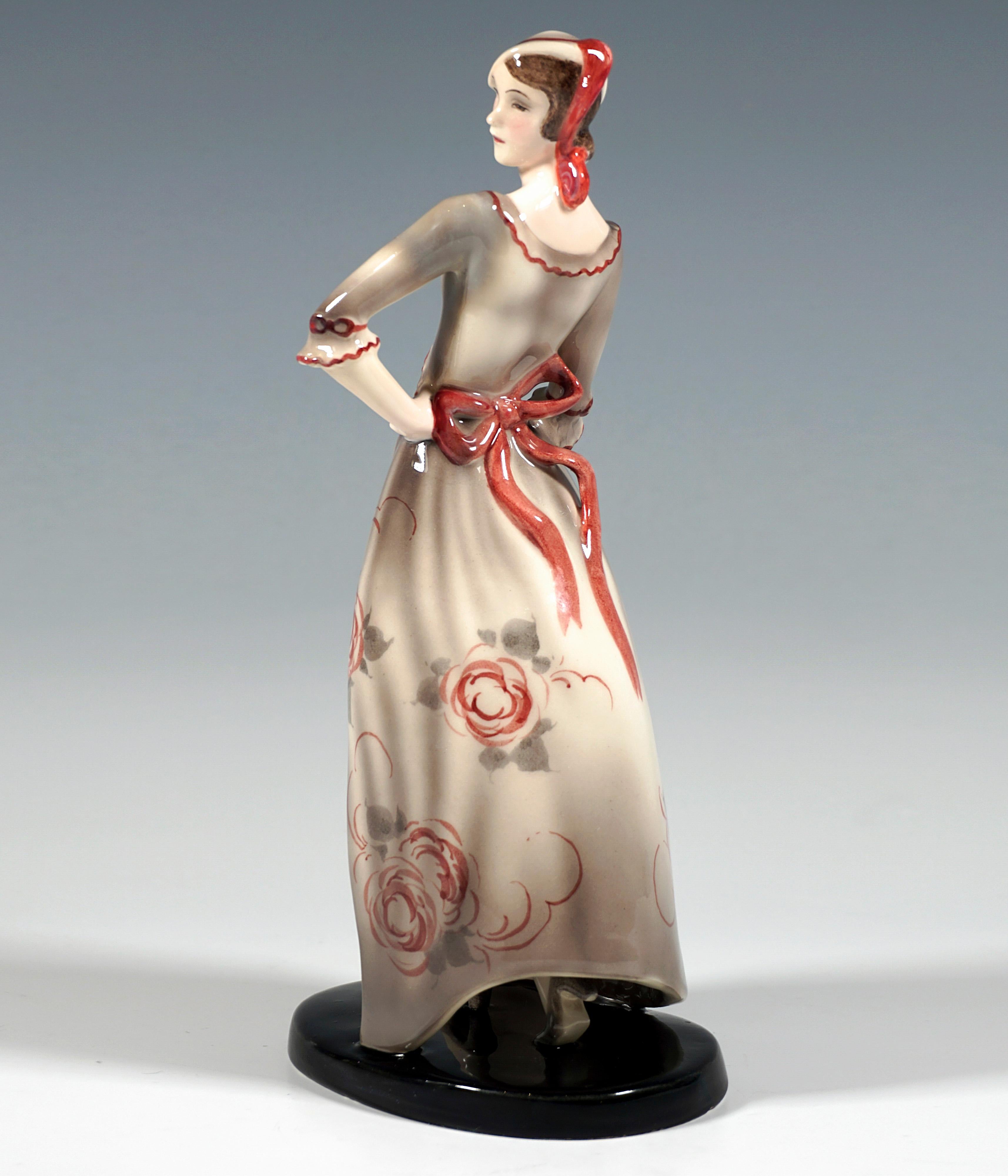 Raffigurazione di un'elegante giovane donna in posa con un abito lungo e scollato di colore grigio chiaro decorato con fiori rossi, un grande fiocco rosso legato sul retro, maniche a tre quarti con volant, la parte della gonna gonfiata dal vento in