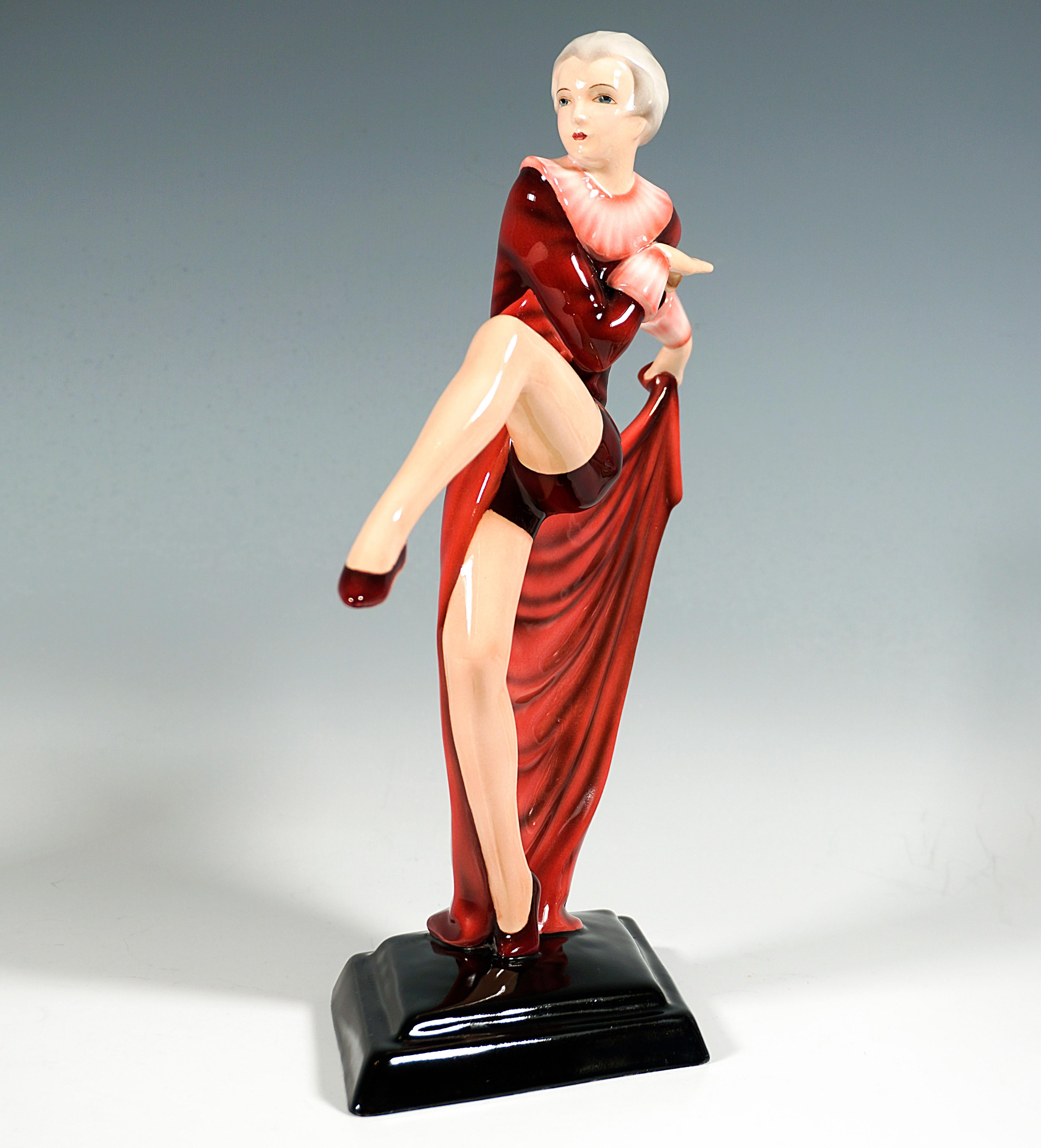 Exquise figurine en porcelaine des années 1930 :
Danseuse Up&Up en costume rouge moulant avec pantalon court et collerette, chaussures de gymnastique aux pieds, en équilibre sur la pointe de l'orteil droit, lançant la jambe gauche vers l'avant,