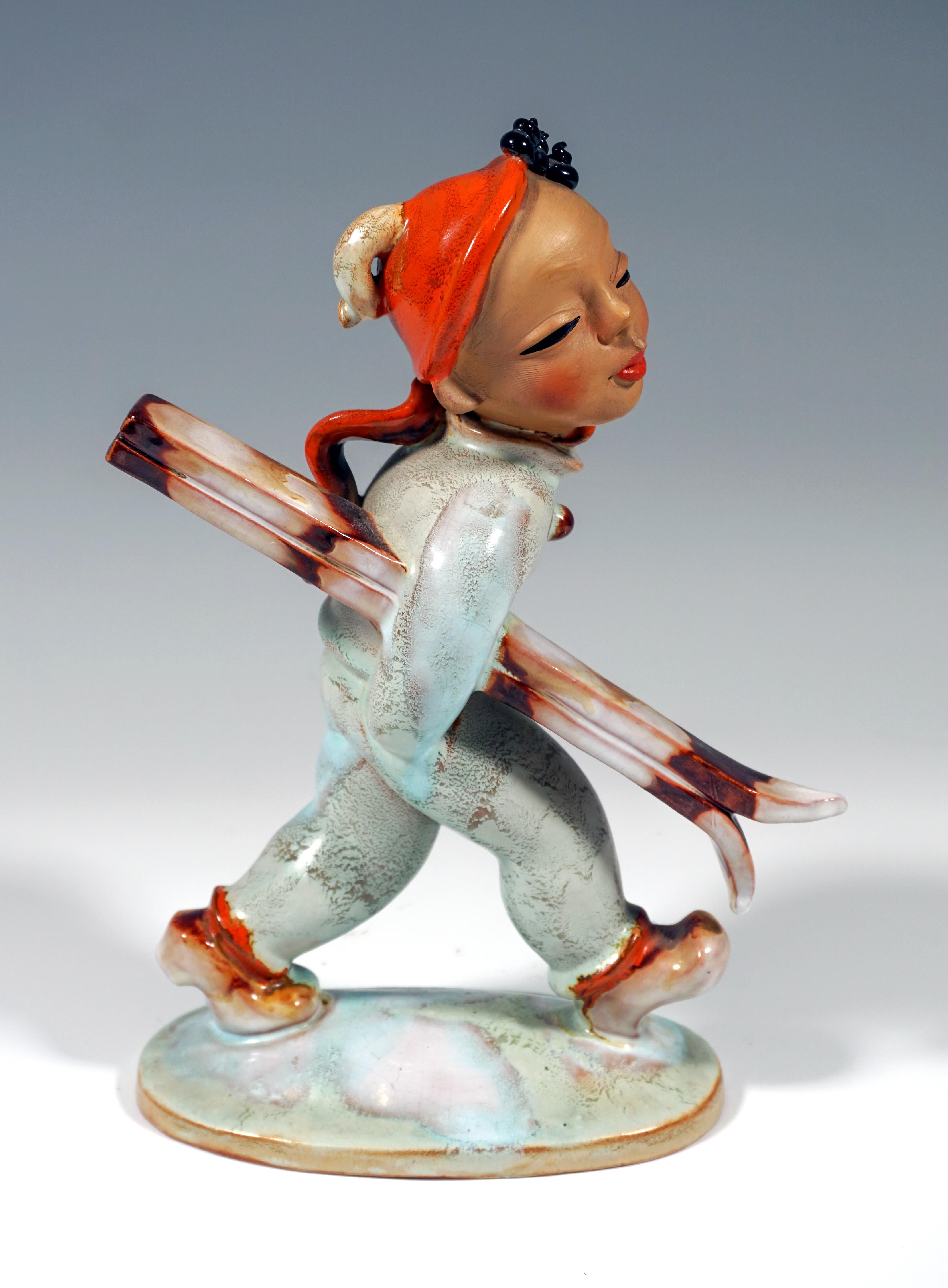 Remarkable Goldscheider Art Déco Figure by Kurt Goebel
The young skier in a light blue overall wears a red CAP, from under which his black curls peek out, and a red scarf. Clutching his skis under his right arm, he walks along.
On an oval snow