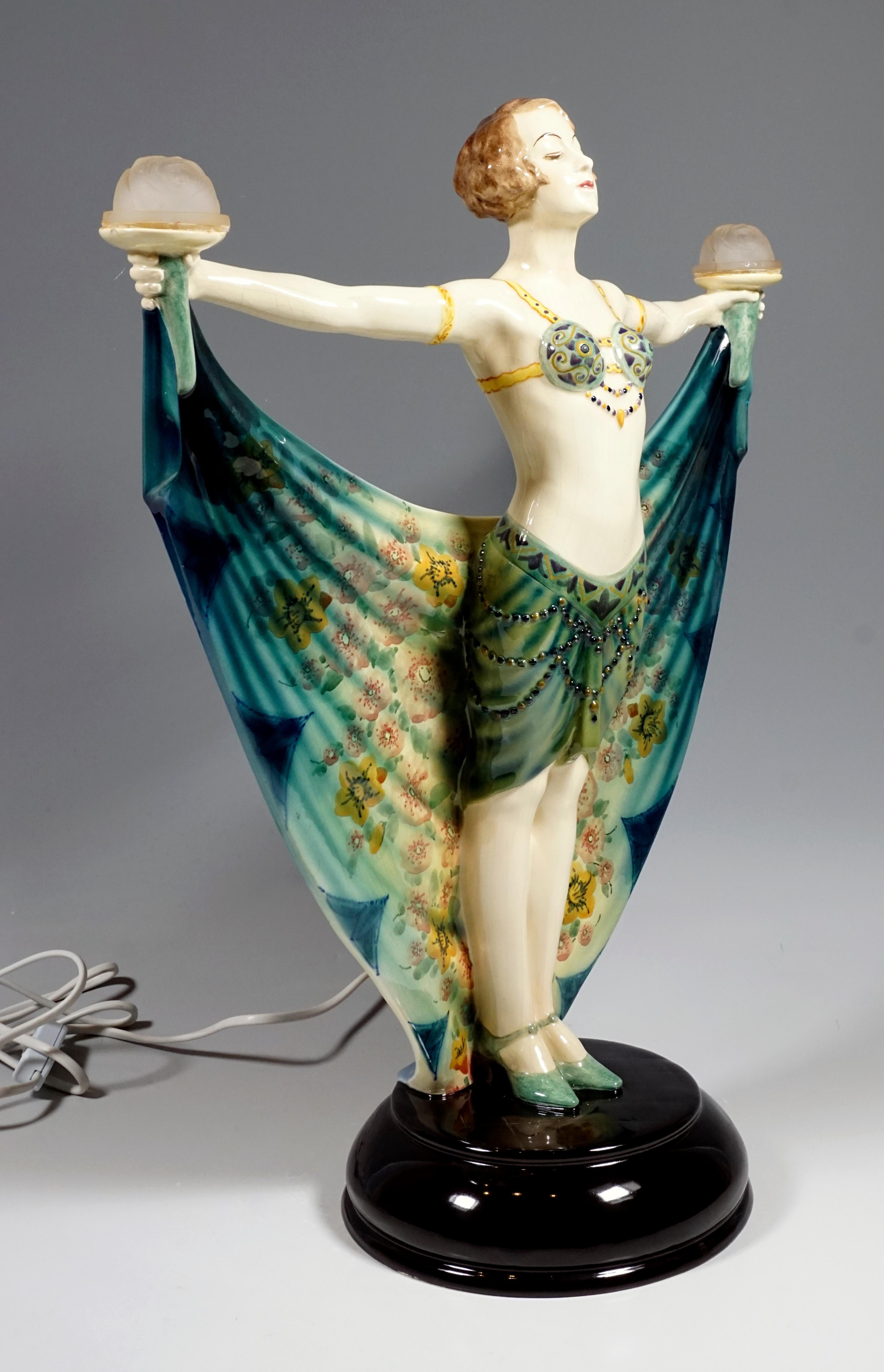 Very rare goldscheider ceramic figure
Most likely Dolores Del Rio, a Mexican film actress, is depicted. She wears a delicate bustier, which essentially consists of two green, ornate shells, which are held together by ribbons and chains, and a short