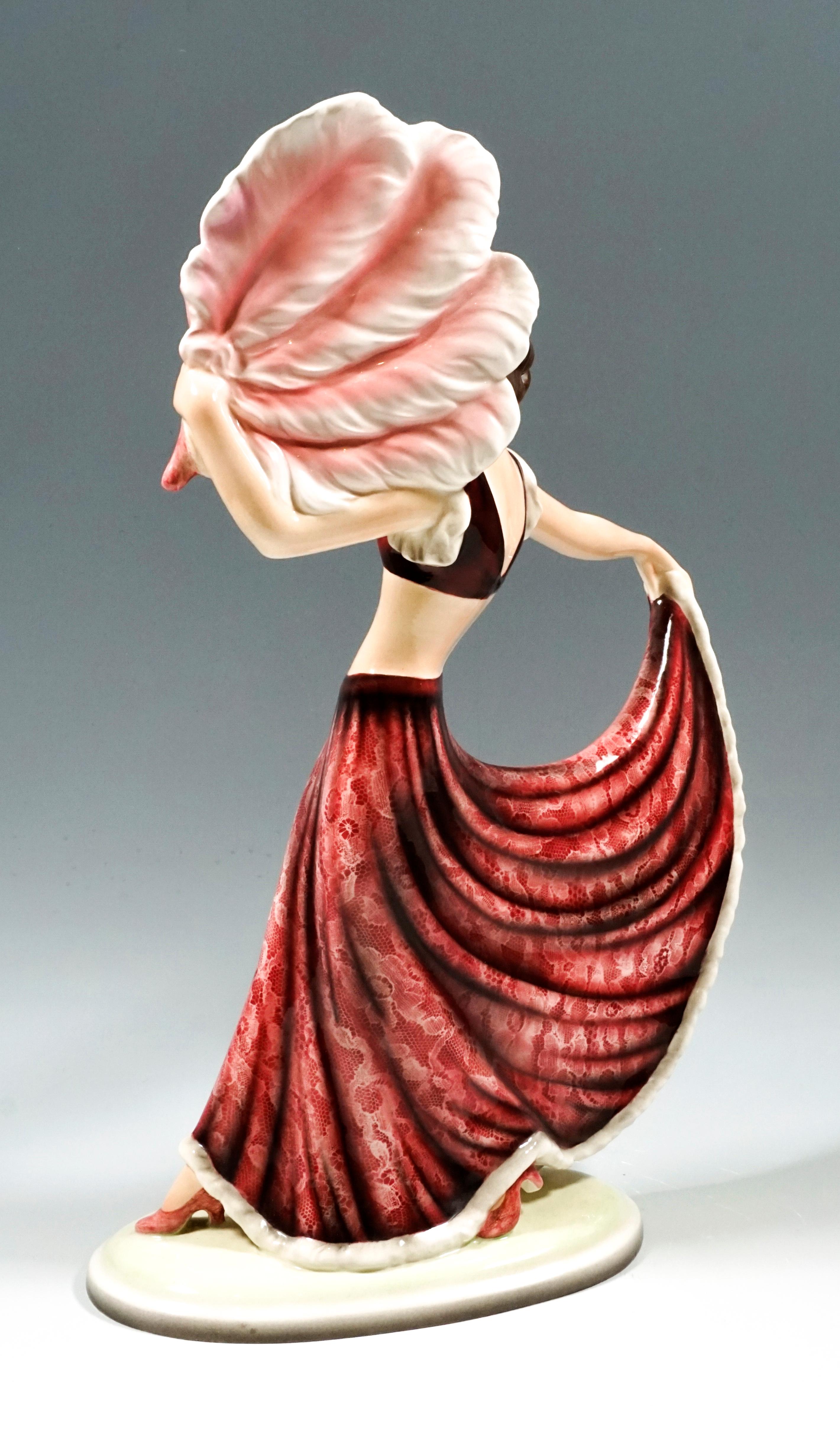 The dancer with shoulder-length, brunette hair wears a long, wide skirt with a white lace pattern and a matching red bustier. Looking to the right, she takes a big step with her right leg and holds the hem of her skirt up with her right,