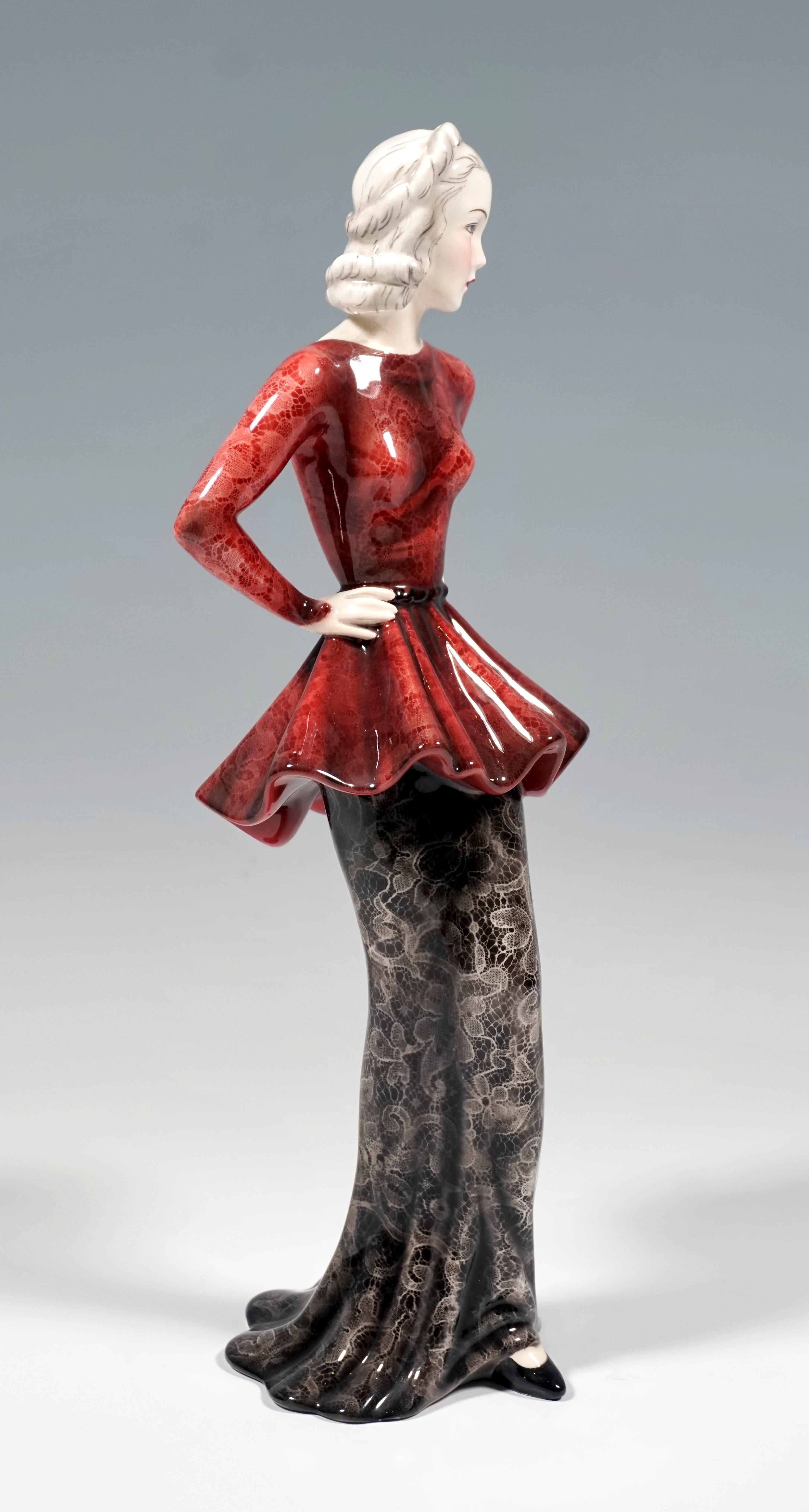 Depiction of Marlene Dietrich as a woman of fashion in a long, narrow lace skirt in black with a red, low-cut, waisted top, her arms on her hips. Her pointed black shoe protrudes from under the robe in front.
The figure is based on the skirt hem