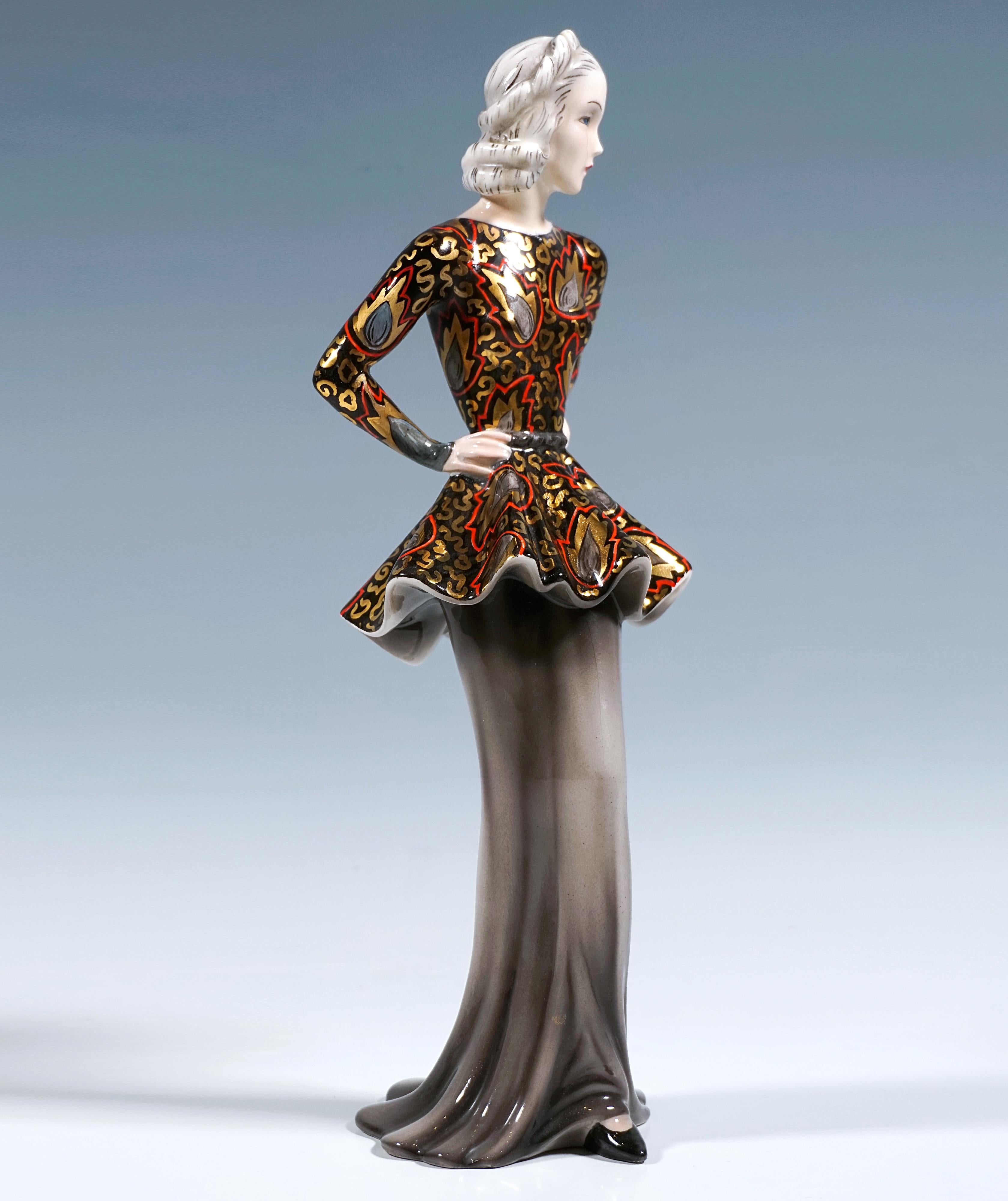 Un design très rare et inhabituel :
Représentation de Marlene Dietrich en fashionista, vêtue d'une longue jupe gris clair à l'ourlet large qui touche le sol et s'enroule autour de ses jambes fines. Elle porte un haut noir, décolleté et ajusté, avec