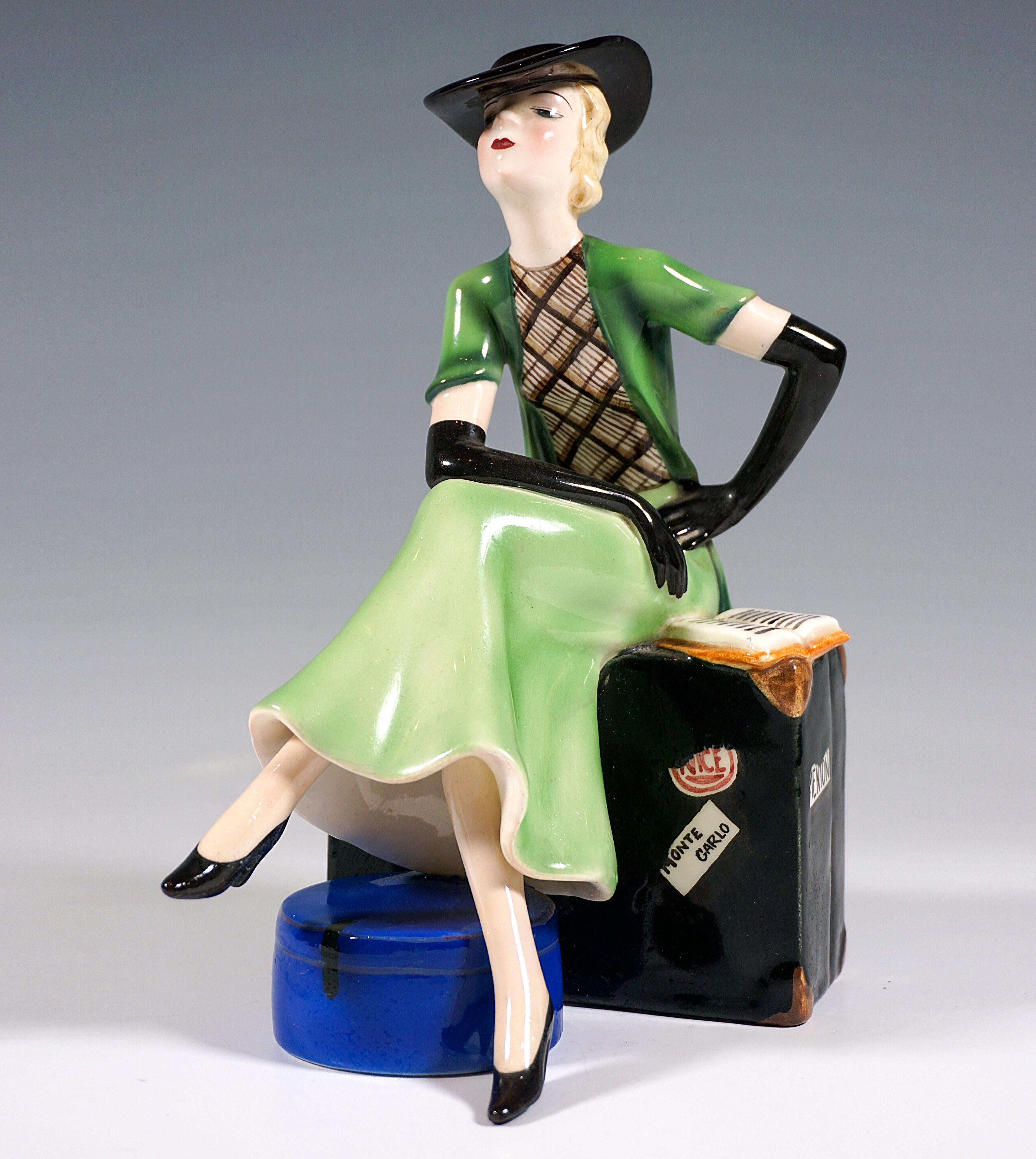 Rare and DelicateGoldscheider Art Déco Ceramic Figurine of the 1930s:
Young lady with chin-length blond hair and elegant black hat, green skirt and black and white top, over it short-sleeved green vest and black long gloves with legs crossed and