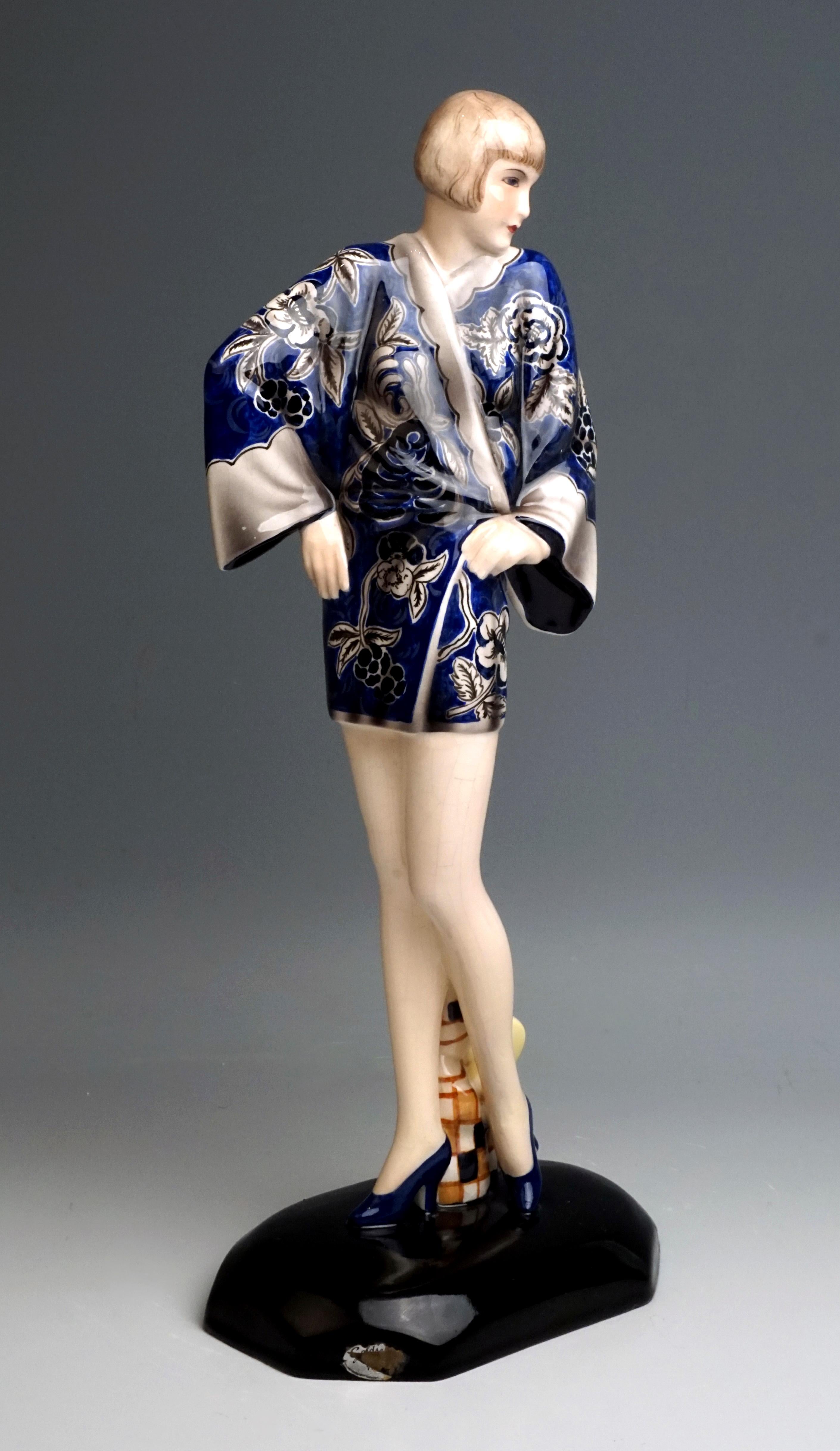 Rare Goldscheider figurine of the 1930s

Young blonde lady with bob hairstyle standing upright, torso turned to the left and supporting both arms on the hips, in a short blue kimono with a floral pattern and high heels. Behind her between her legs
