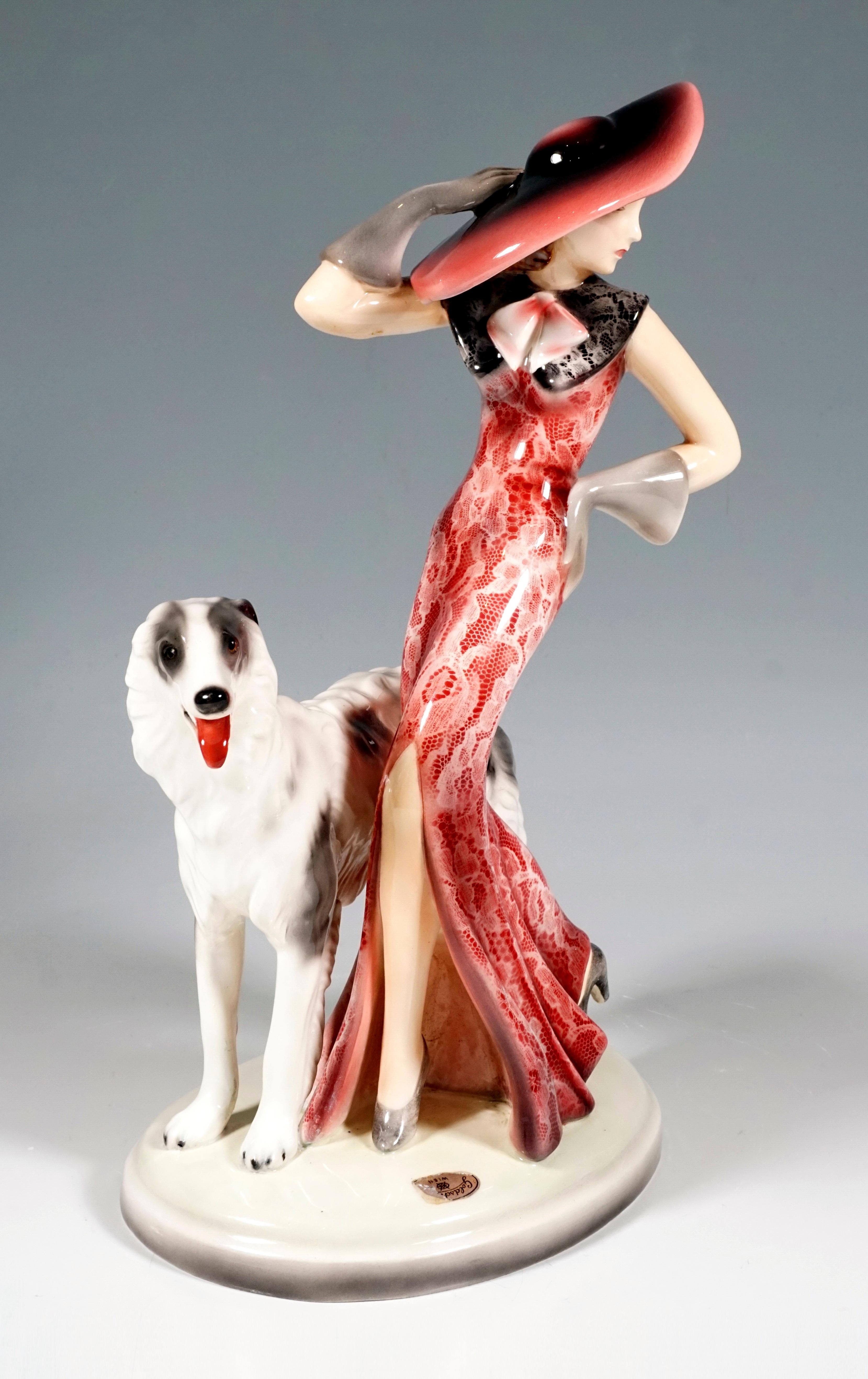 Darstellung einer eleganten Dame in einem langen, eng anliegenden roten Kleid mit weißem Spitzenmuster und einem weit schwingenden Rockteil mit hohem Schlitz an der Vorderseite, einem breiten, schwarzen Spitzenkragen und einem breitkrempigen Hut,