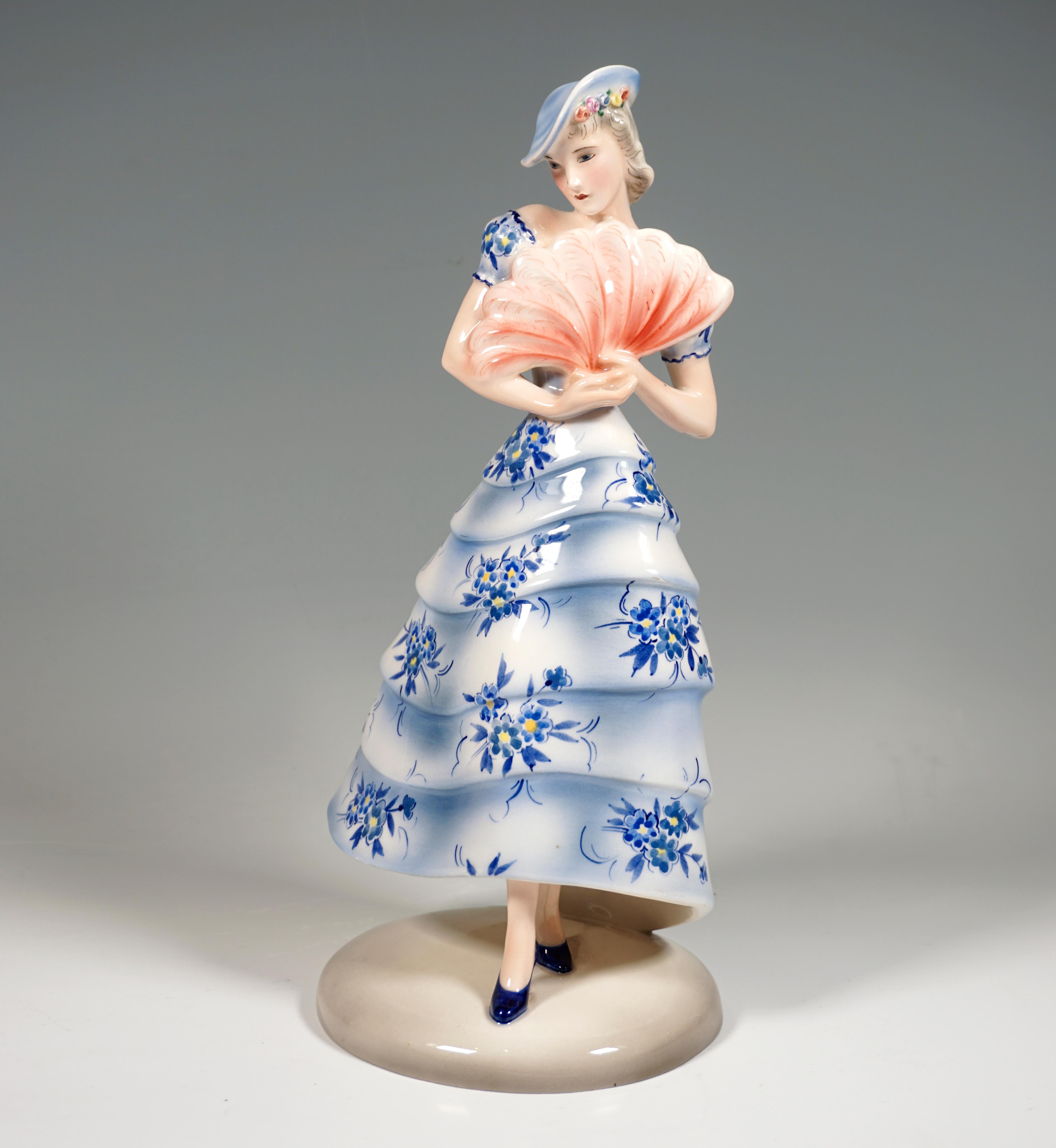 Very Rare Goldscheider Vienna Figurine of the late 1930s:
Representation of an elegant dancer in a long, flowered summer dress with a flounced skirt with floral decorations and matching hat, her head tilted slightly to the right in a pose, holding