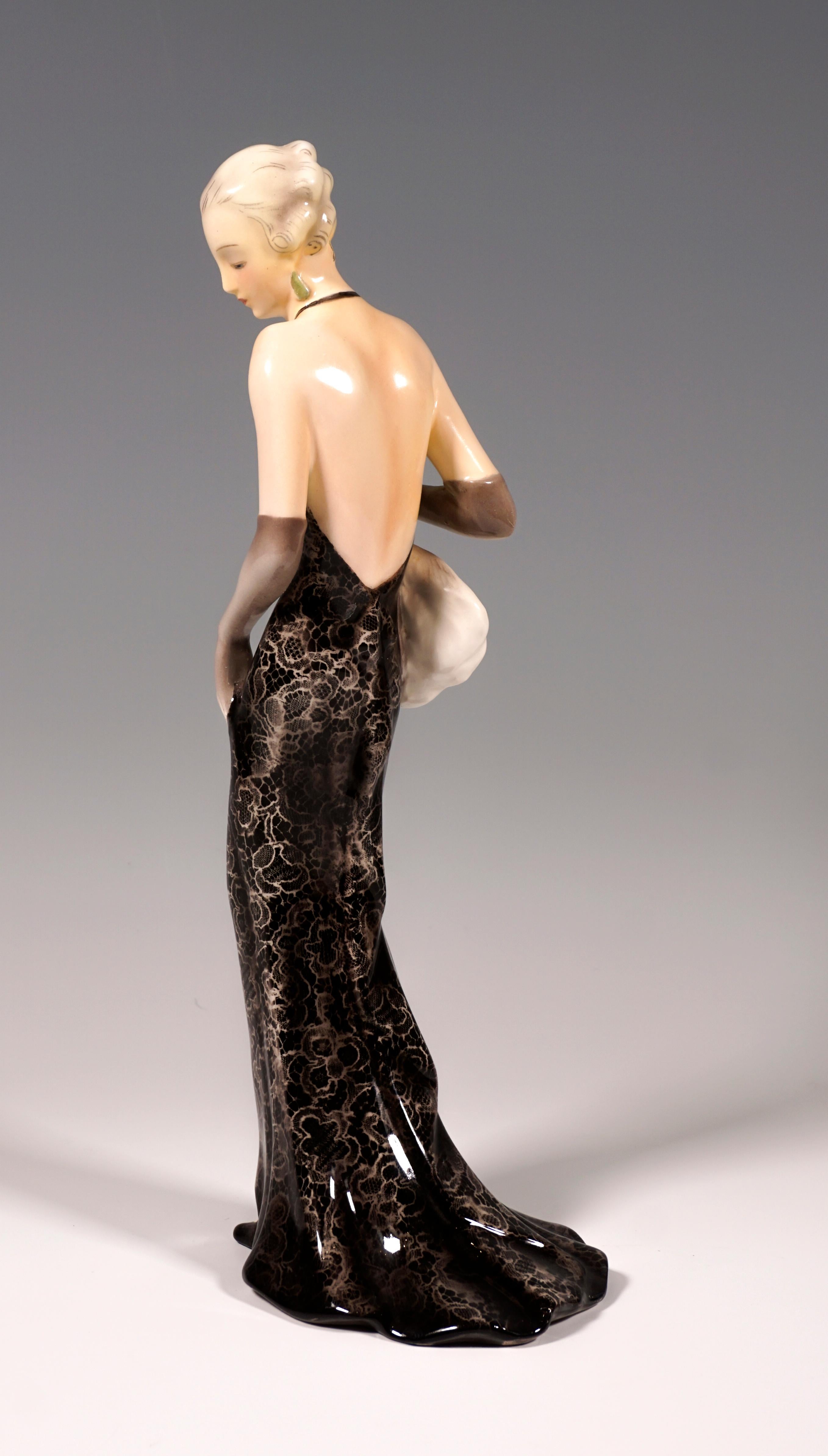 Very rare goldscheider Vienna figurine of the 1930s:
Depiction of an elegant lady in a long, tight-fitting, backless dress made of black lace and a wide skirt part. She also wears long gray gloves, her hair pinned up and matched to the color of the