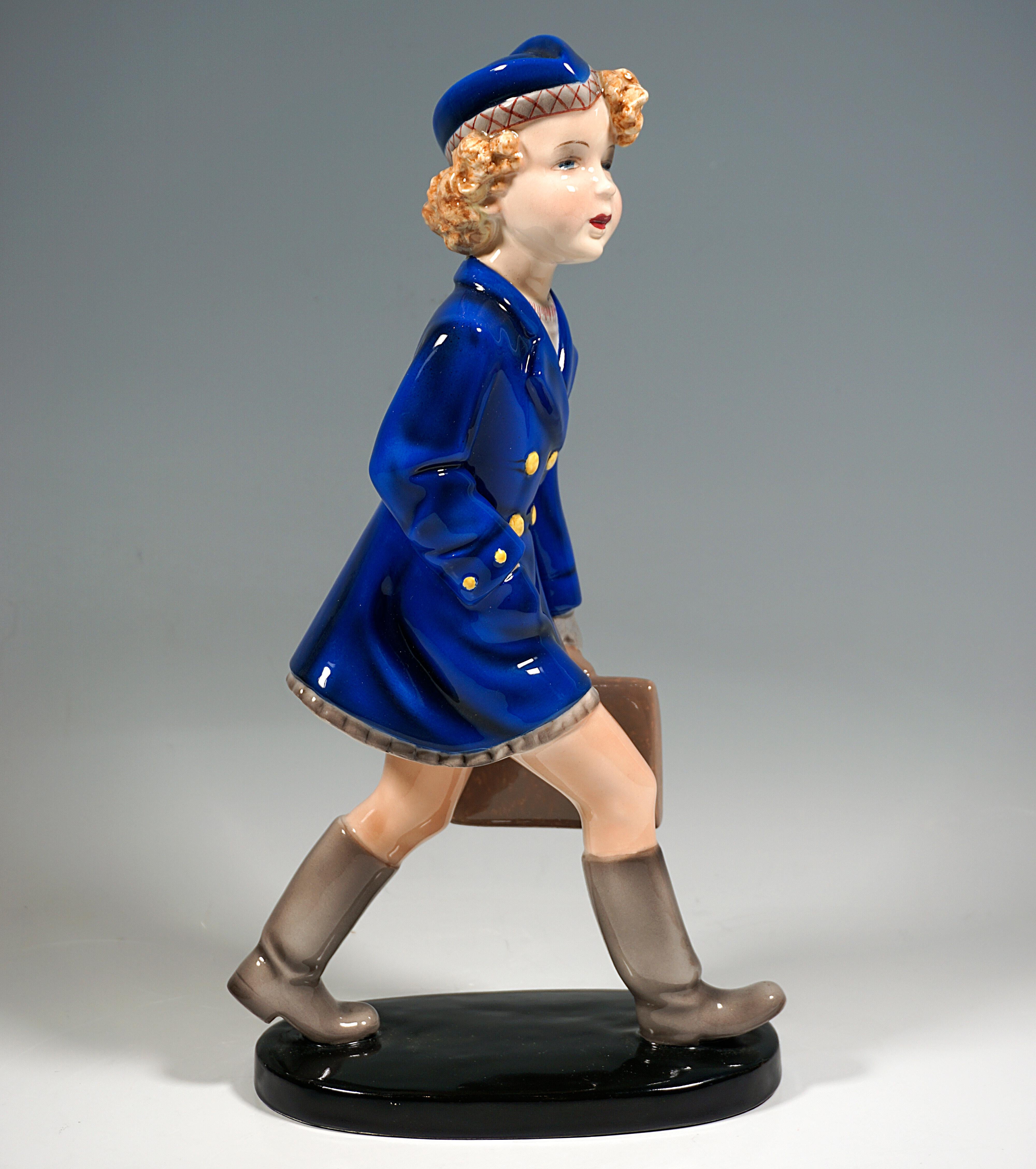Très rare et exceptionnelle figure en céramique d'art Goldscheider de la fin des années 1930 :
Fille marchant en manteau bleu sur une robe beige et un chapeau bleu assorti avec une bordure beige avec un motif de broderie rouge, des bottes et des