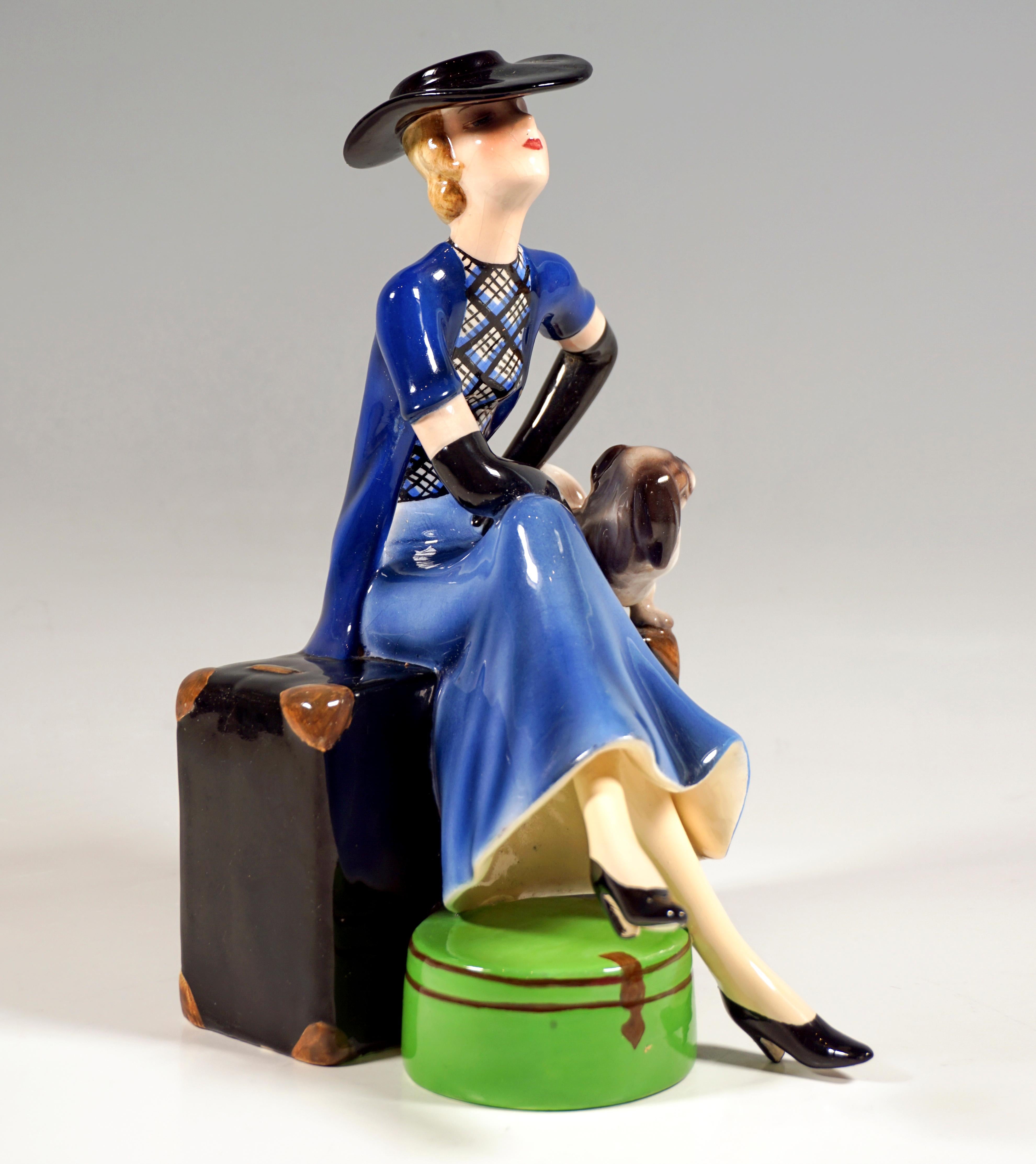Rare and delicate Goldscheider Art Déco ceramic figurine of the 1930s:
Young lady with chin-length blond hair and elegant black hat, blue skirt and checked blouse, short-sleeved black waistcoat and long black gloves with her legs crossed and her
