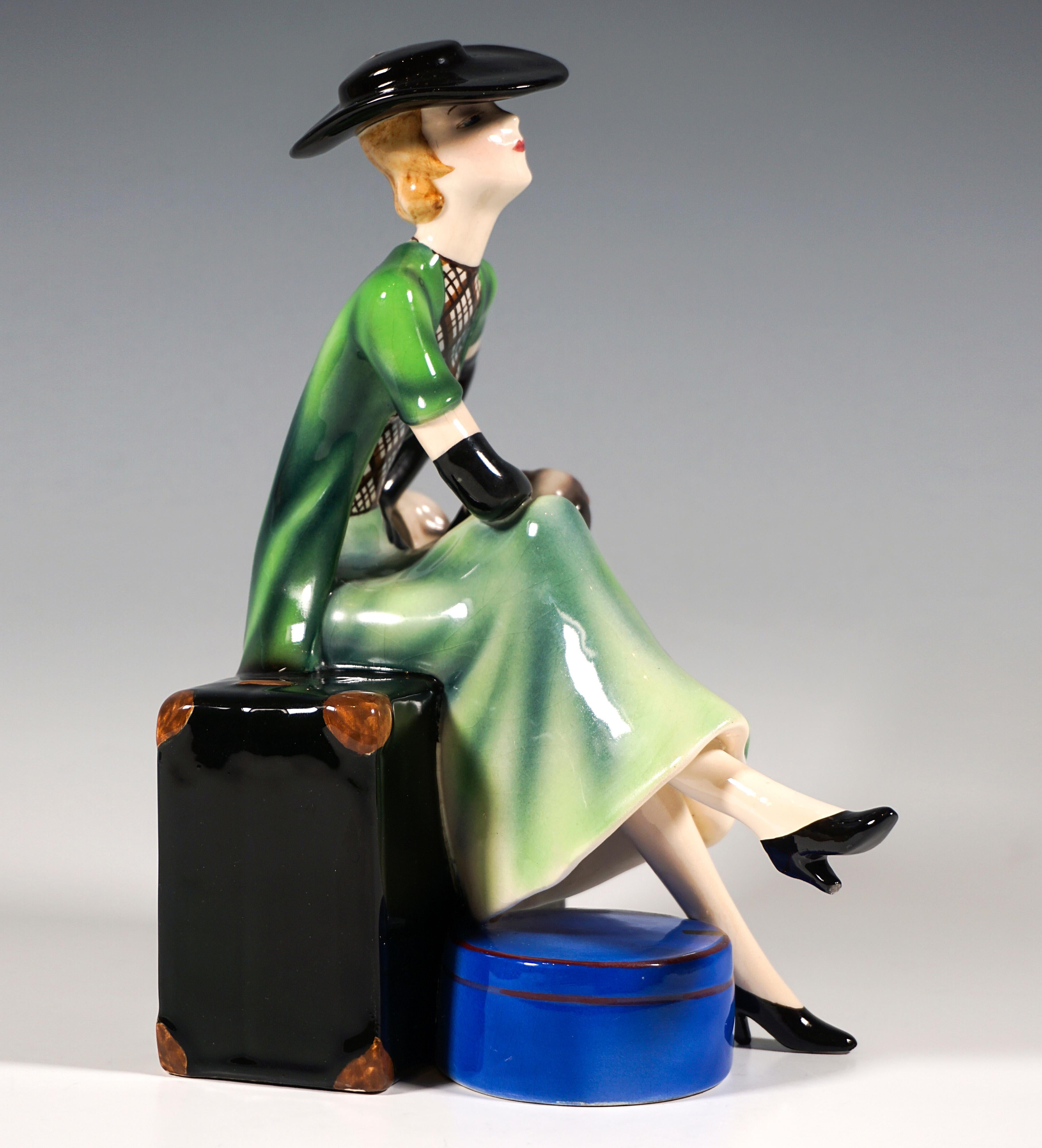 Rare and delicate Goldscheider Art Déco ceramic figurine of the 1930s:
Elegant young lady with chin-length blond curls and elegant black hat, green long skirt and white and black checkered blouse, wearing a short-sleeved green vest and long black