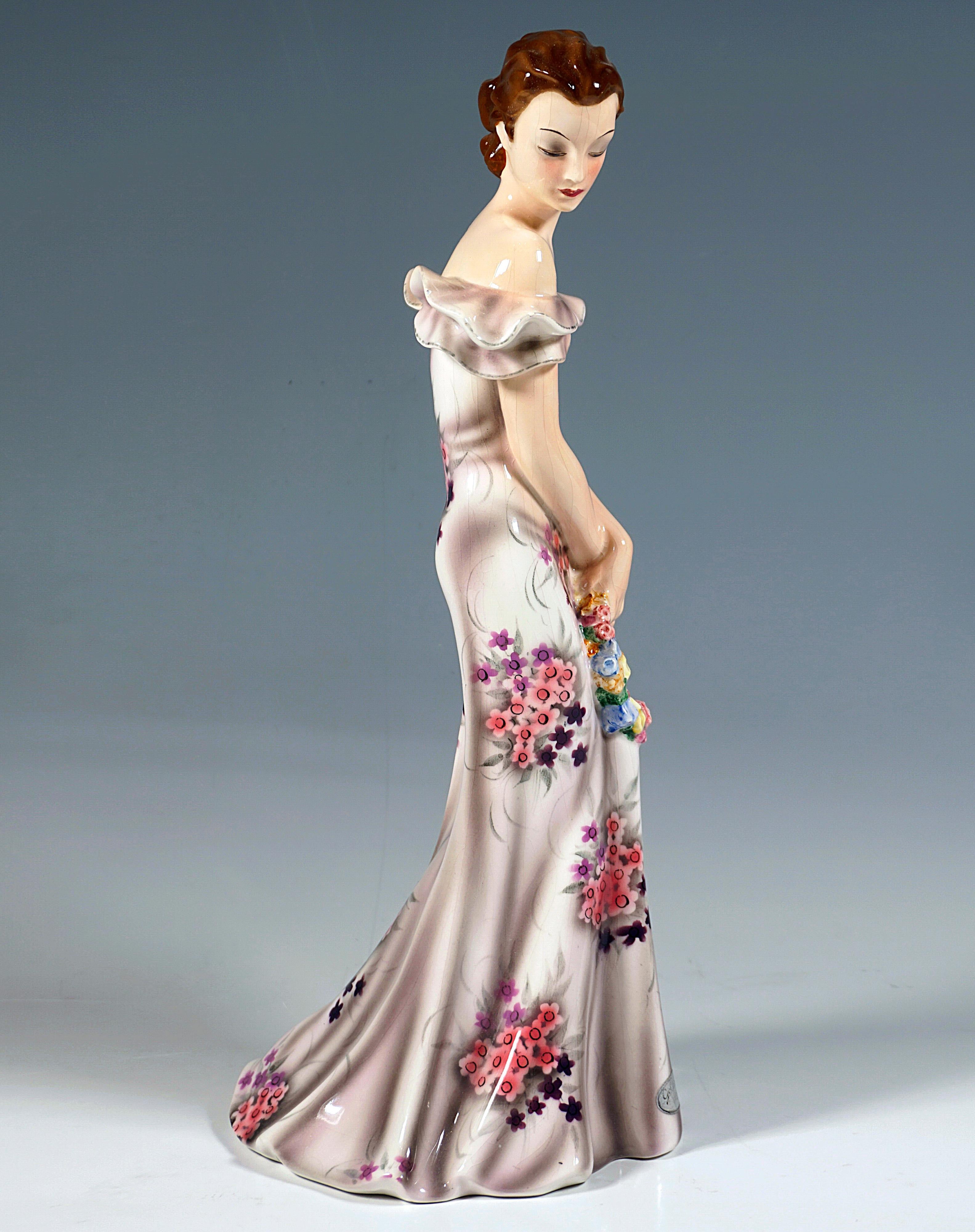 Rare Goldscheider Vienna Figurine of the late 1930s:
Representation of an elegant lady in a long, close-fitting, off-the-shoulder dress with a ruffled neckline made of rose-colored fabric with floral decoration and a floor-length, wide skirt, her
