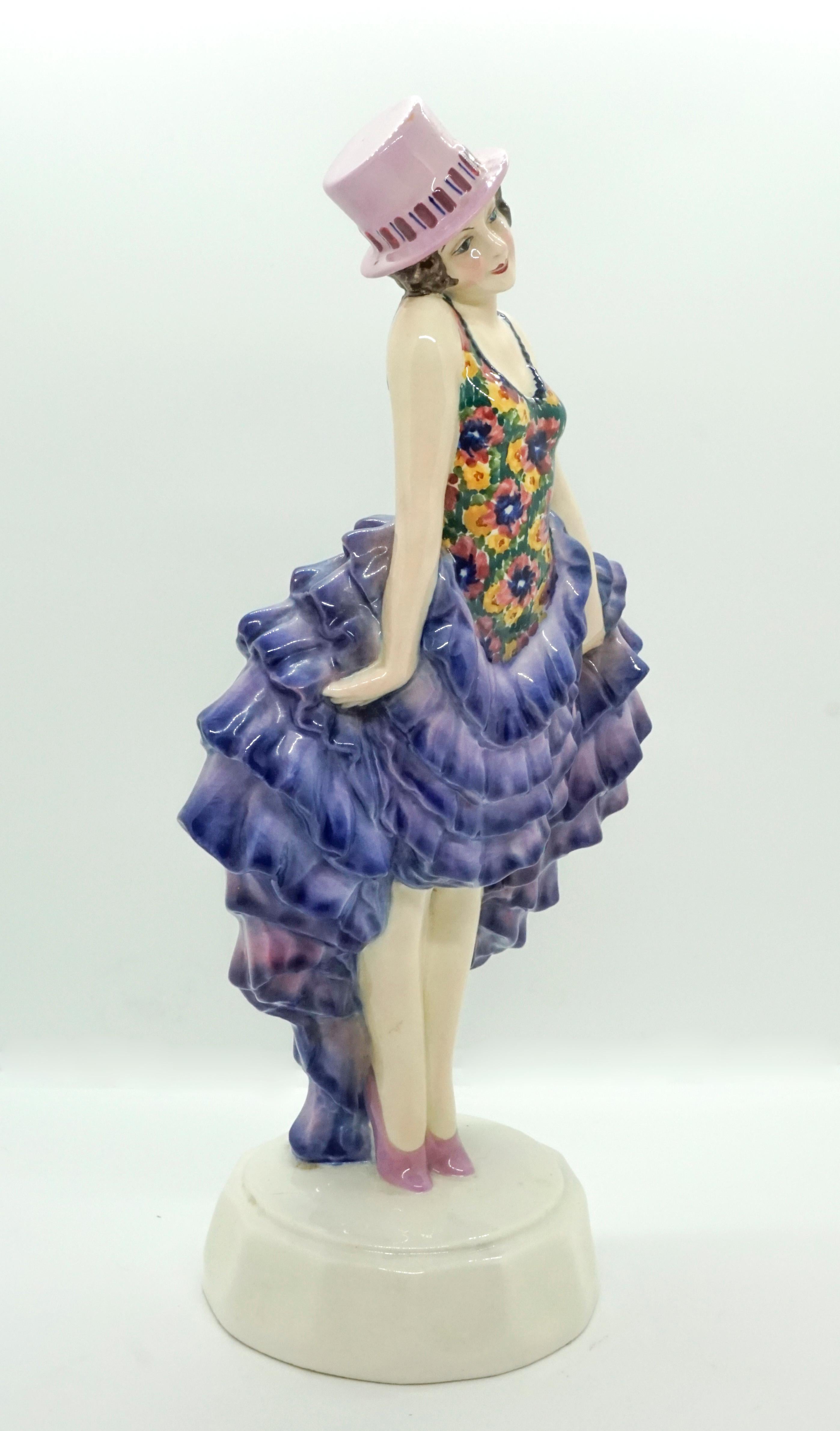 Rare Goldscheider figure of the 1920s.
The standing dancer wears a pink cylinder hat on her short brown locks. The flower-patterned top of her costume is tight-fitting and sleeveless. Tilting her head slightly to the right, she pulls up her