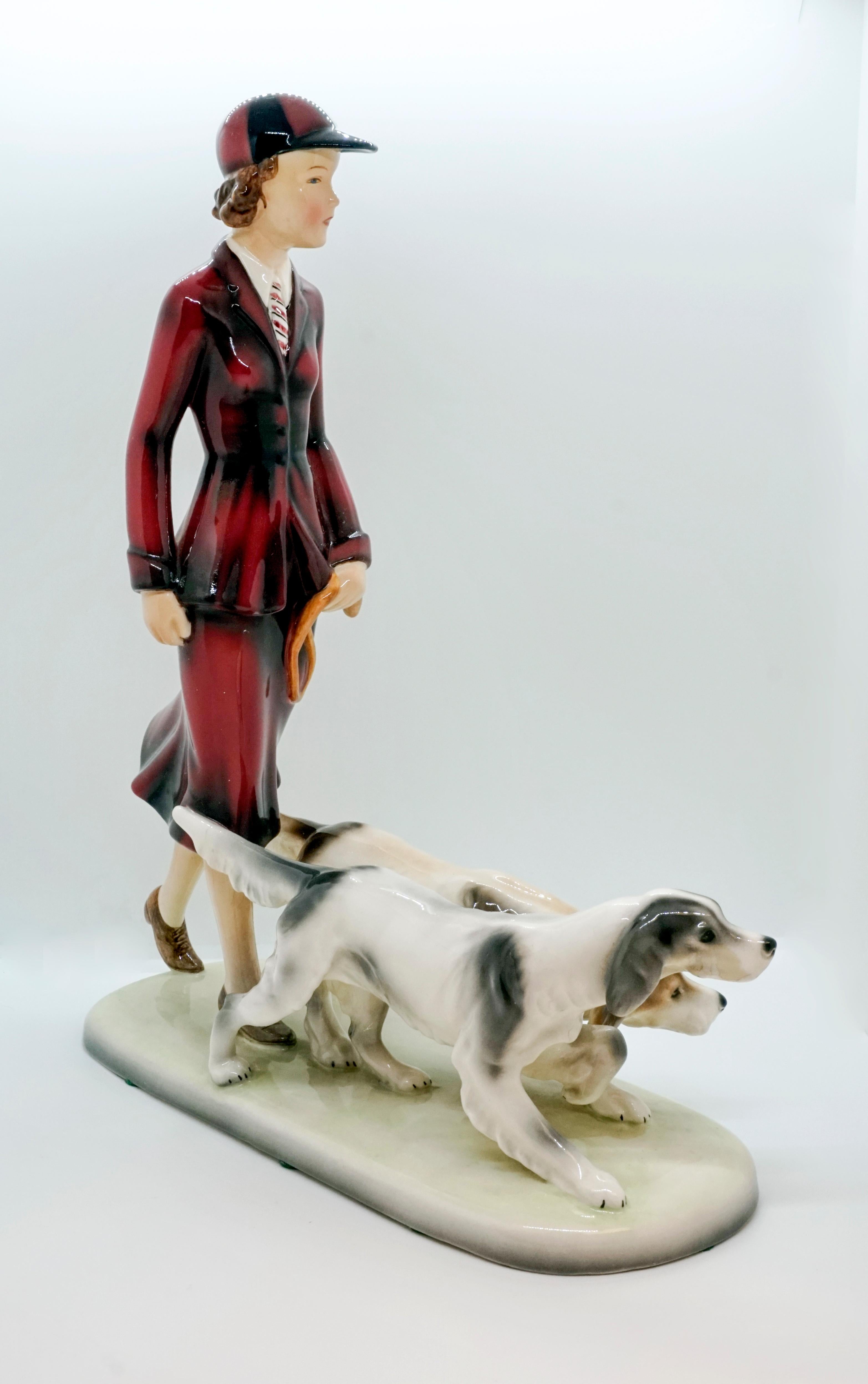 Rare Goldscheider figurine of the 1930s

Young lady with dark blond curly hair and a cap in a sporty costume with skirt and tie running two English pointer hounds.
On a cream-colored rounded rectangular base.

Designed by Stefan Dakon
