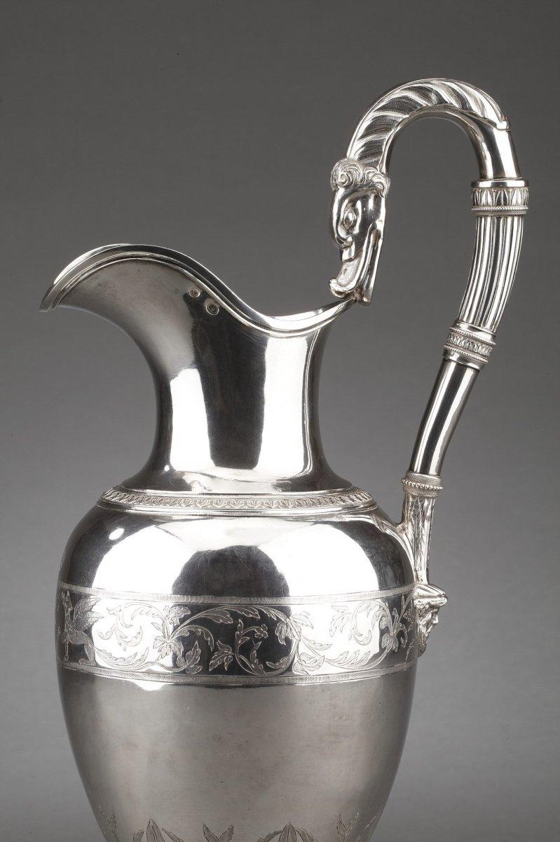Ewer in solid silver mounted on a pedestal decorated with palmettes, the ovoid body is finely chiseled with a mid-length plant frieze and flanked by an applique handle with mascaron head and pouring duckbill.
Dimensions: height 33 cm - base diameter