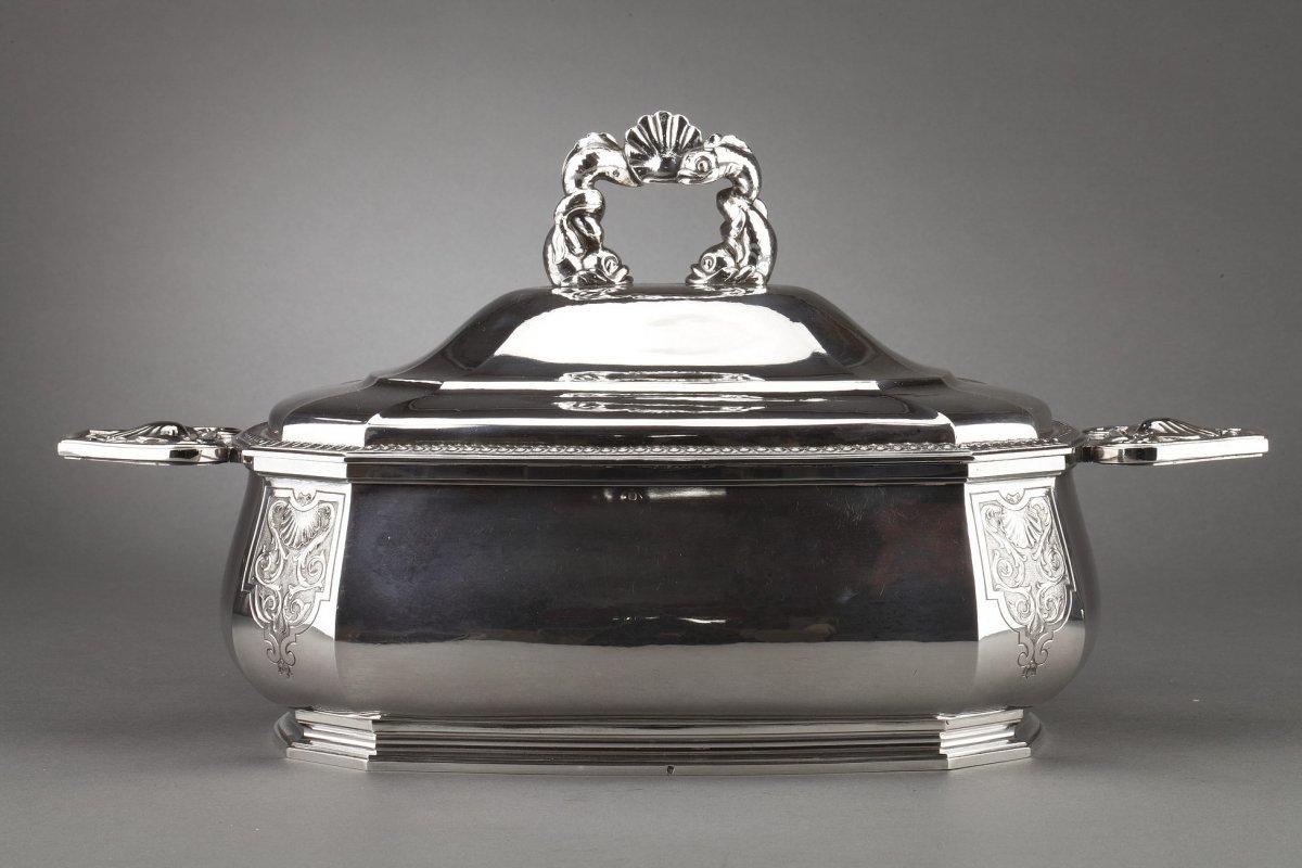 Centerpiece represented by a solid silver octagonal tureen. the domed body is engraved on four sides with a decoration of foliage and shell arabesques, flanked on each side by chiseled handles. The oval lid is surrounded by a frieze and surmounted