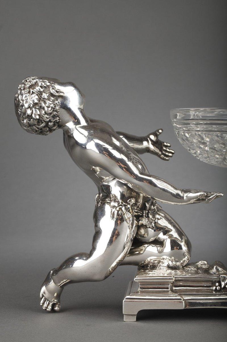 Centerpiece in silvered bronze composed of a cut crystal cup placed on a pedestal and supported by two puttis
Dimensions: length 44 cm - cup diameter 22 cm height 16.5 cm
Material: bronze and crystal Period: 19th century NAPOLEON III
Goldsmith :