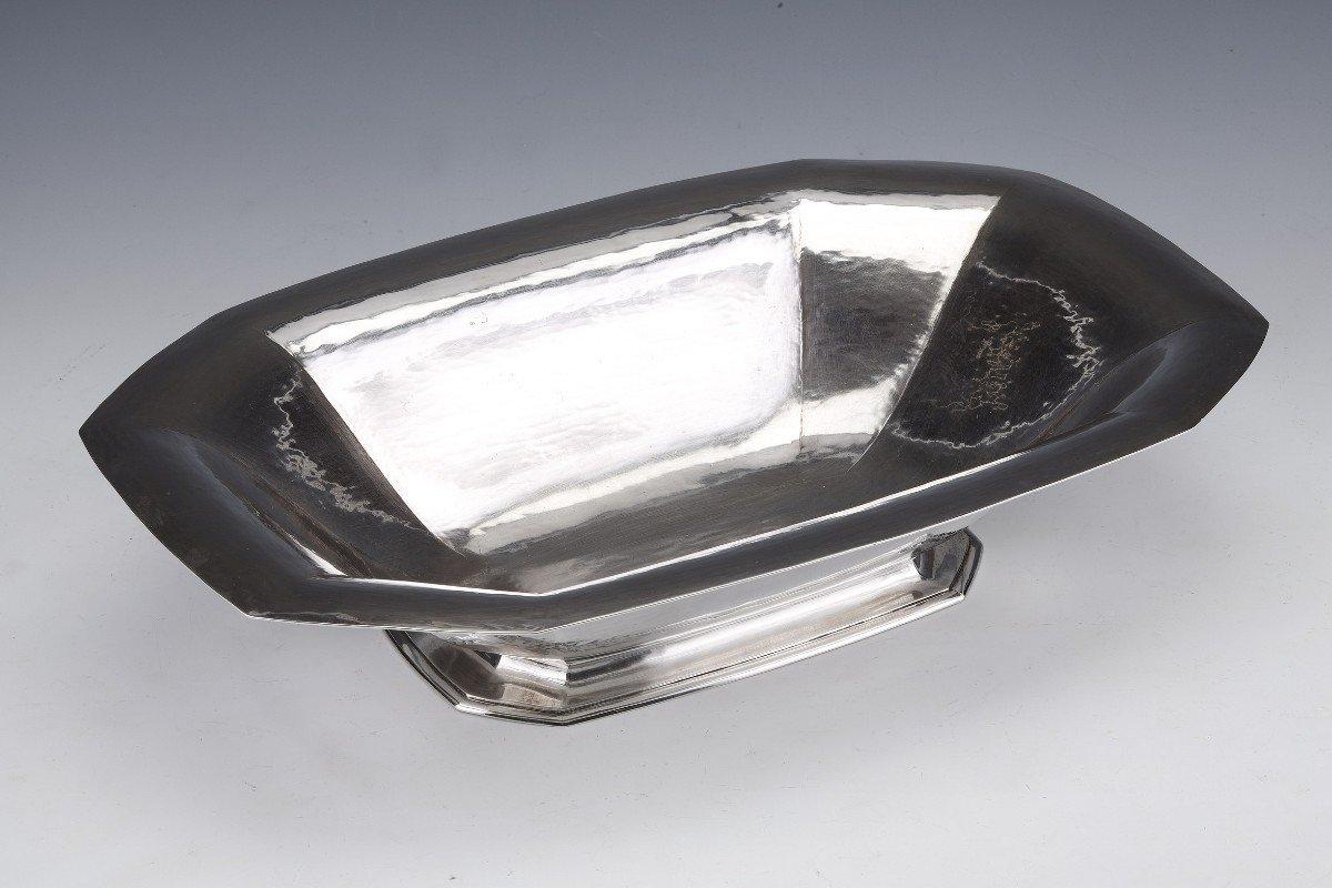 Large solid silver centerpiece plain model mounted on a rectangular and octagonal pedestal on which is placed a hollow cup with canted sides.

Dimensions: length 40 cm width 27 cm height 8.5 cm

Material: silver 1st grade 950/°°°

Weight: 1285
