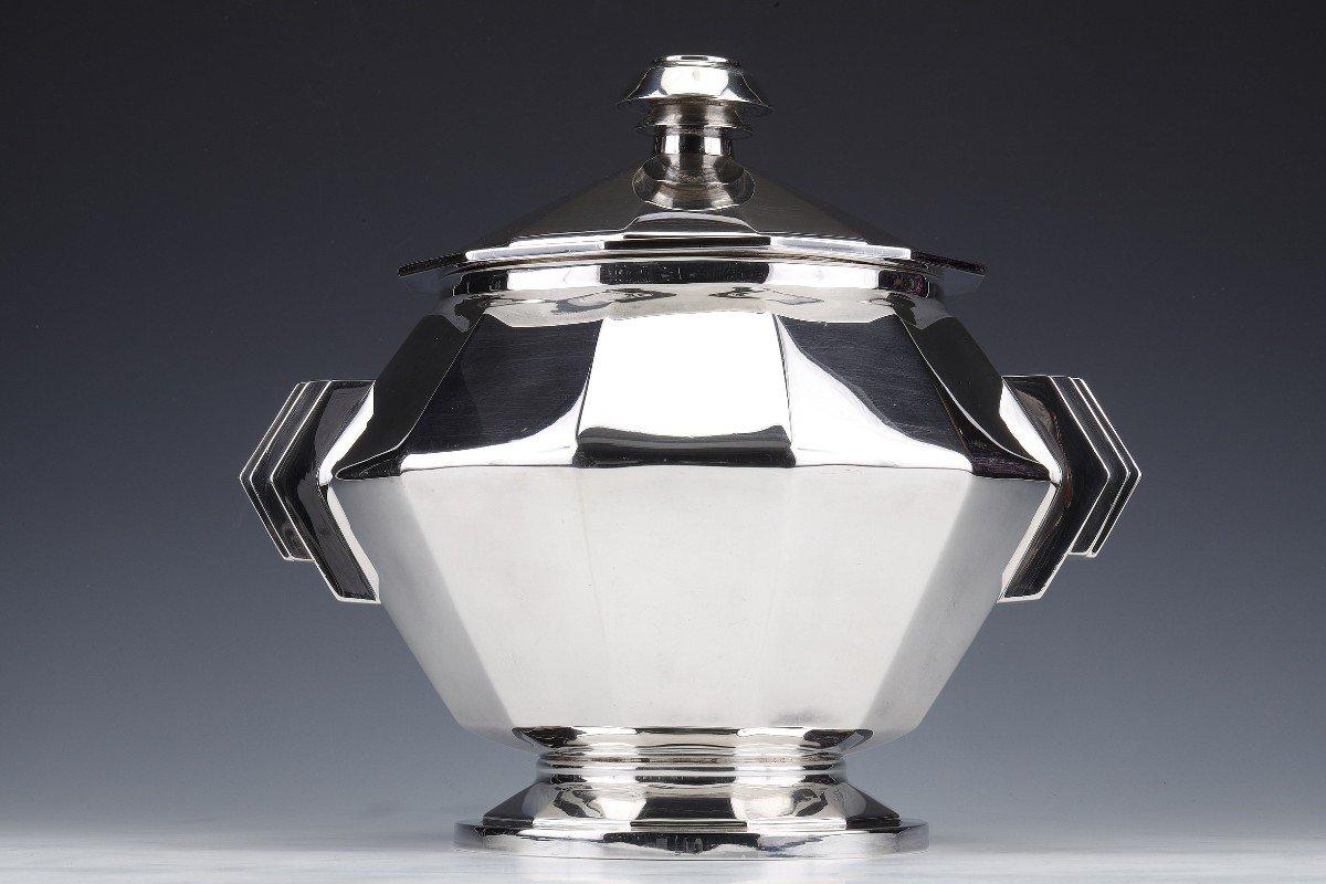Important centerpiece in solid silver represented by an octagonal covered soup tureen with canted sides mounted on a pedestal and flanked by two geometric handles.
Dimensions: height 30 cm - diameter 33 cm with handles
                         base