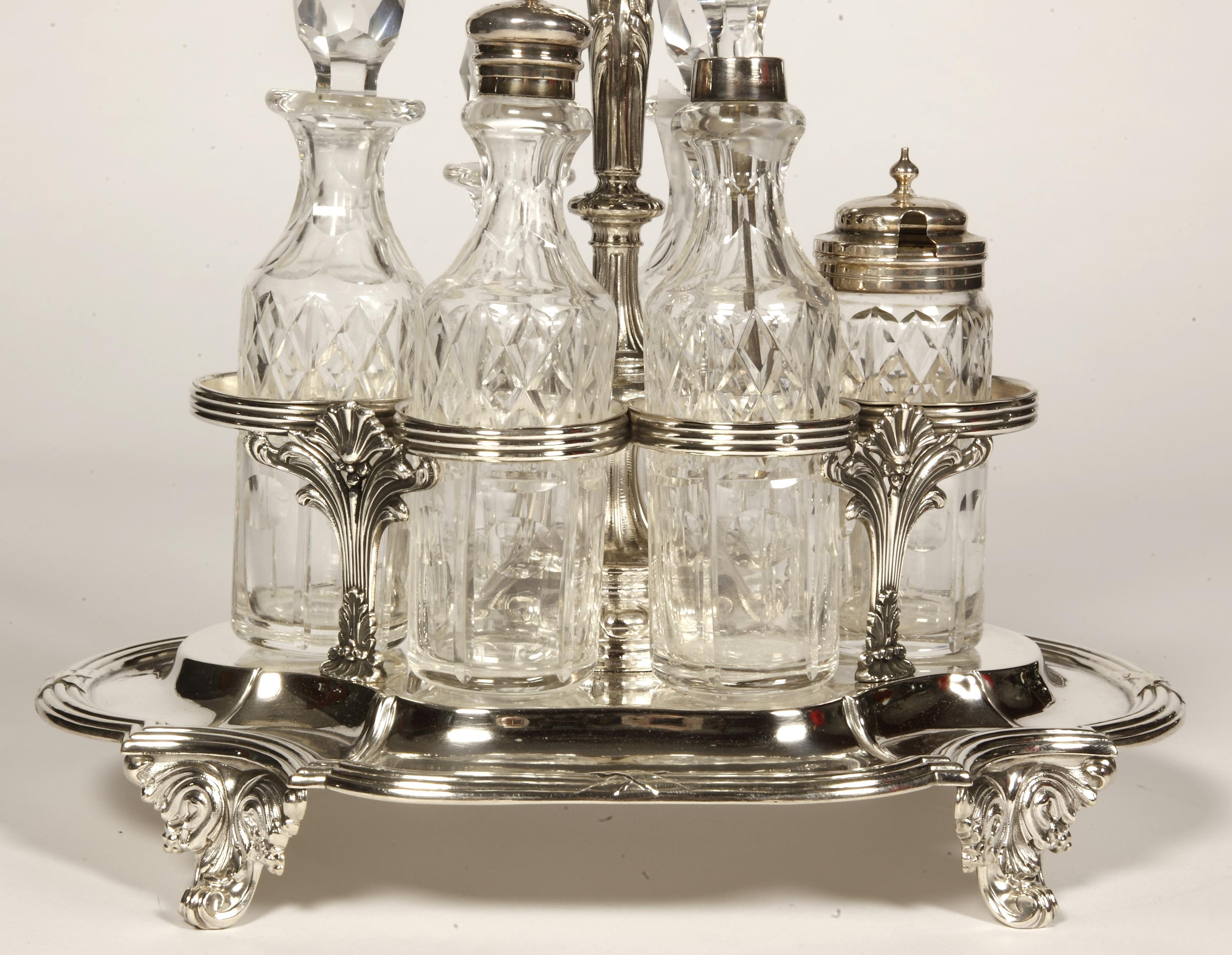 This cabaret is made up of a tray on four leafy feet, surrounded by contoured nets, and surmounted by four pilasters supporting the circles in which the cut crystal bottles are housed. the central stem is terminated by a young fauna. Dimensions: -