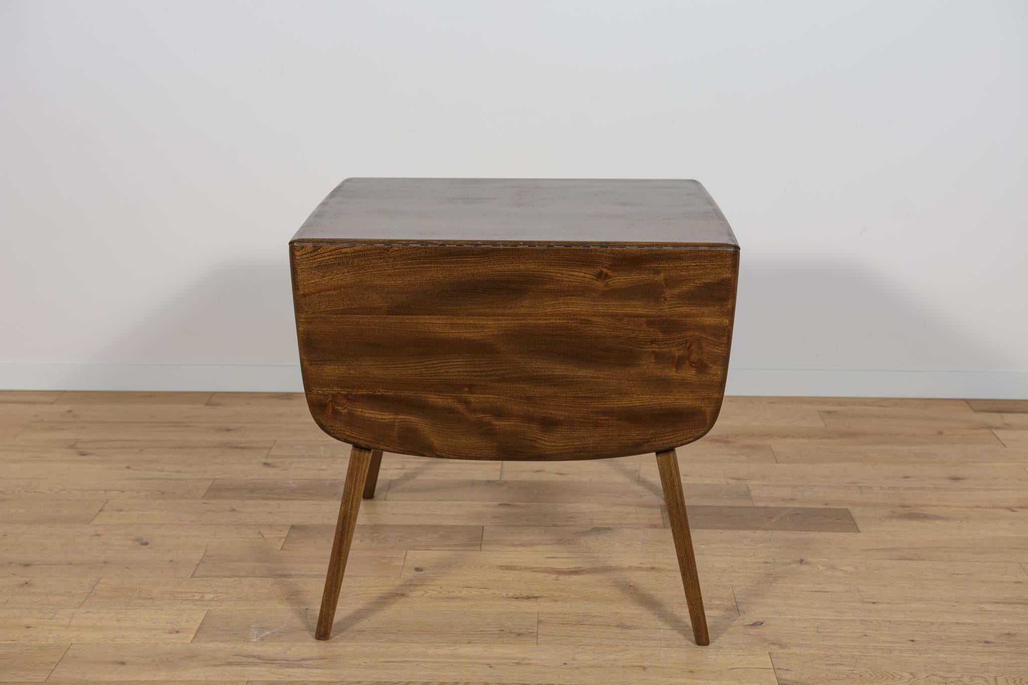 Questo tavolo da pranzo allungabile è stato disegnato da Lucian Ercolani e prodotto da Ercol nel Regno Unito intorno al 1960 come parte della serie Goldsmith Carver. Il tavolo è realizzato in legno massiccio di faggio e olmo. I mobili sono stati