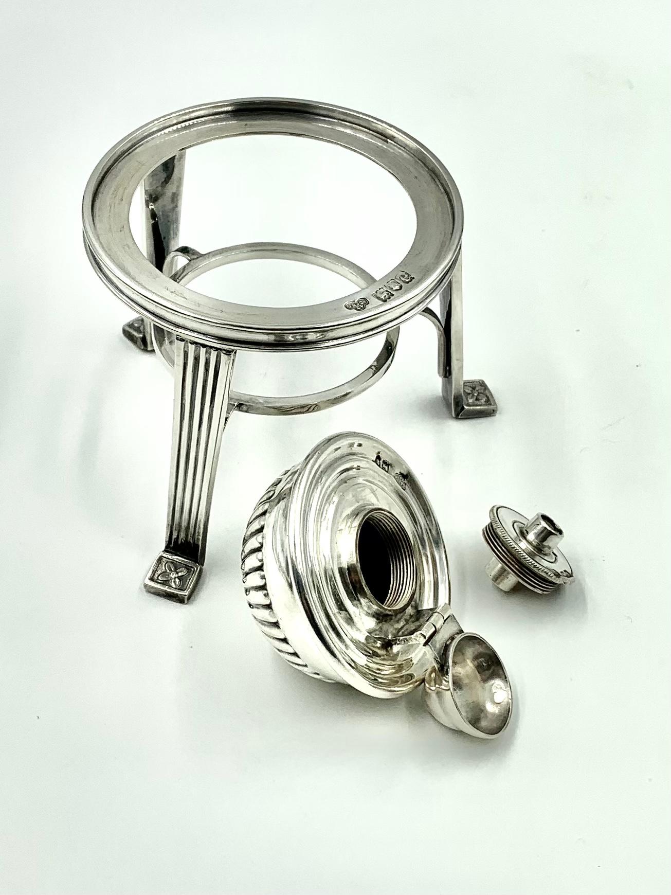 Scarso scaldavivande in argento sterling Goldsmiths & Silversmiths Co. in eccellenti condizioni originali. Si compone di un sostanzioso supporto circolare in argento massiccio su tre gambe affusolate e nervate che terminano in graziosi piedini