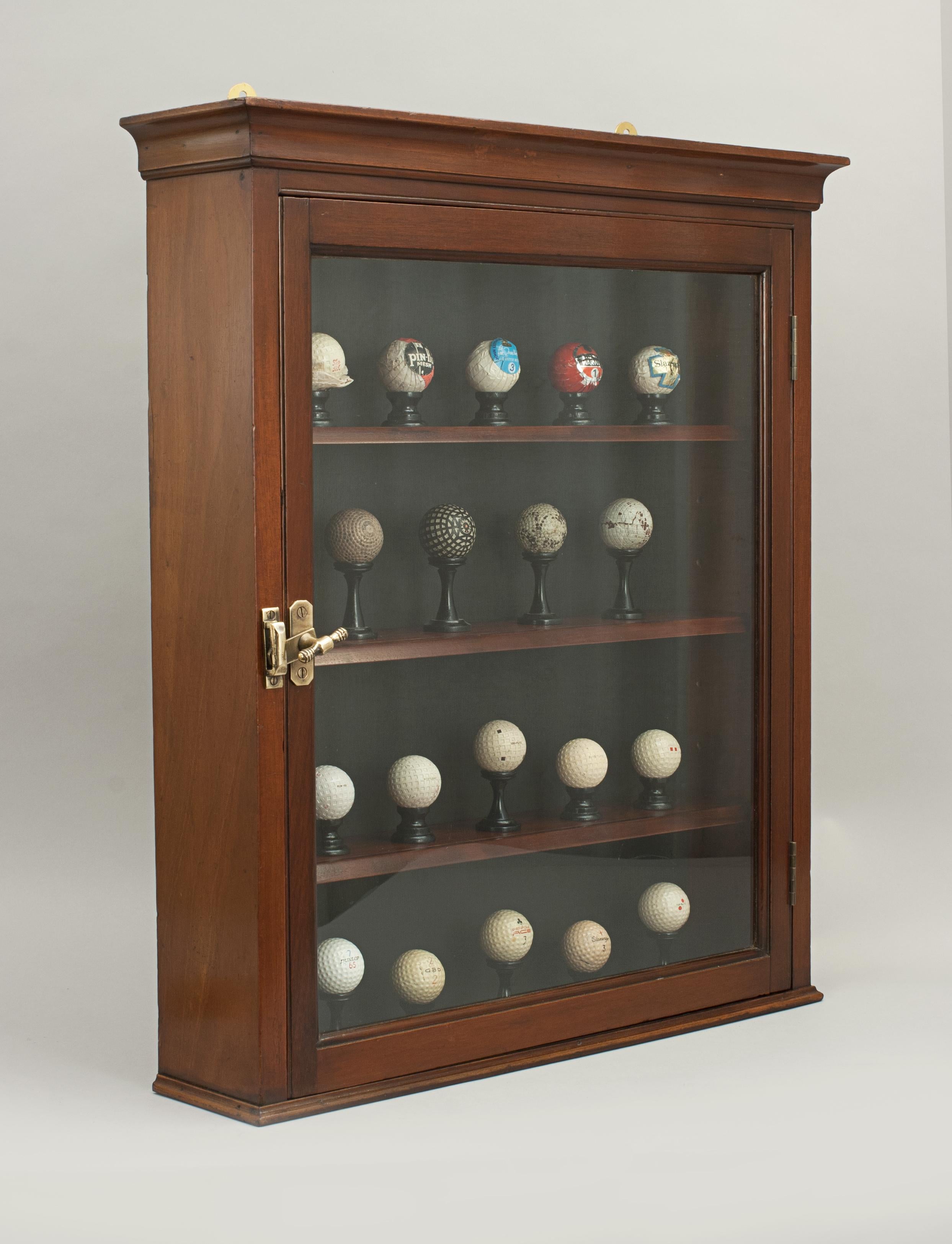 Antique mahogany golf ball display cabinet.
A Victorian wall display cabinet with a display of 19 golf balls. The cabinet is with a single glazed door and a black background. The balls sit on individually turned ebonized wooden display stands. The