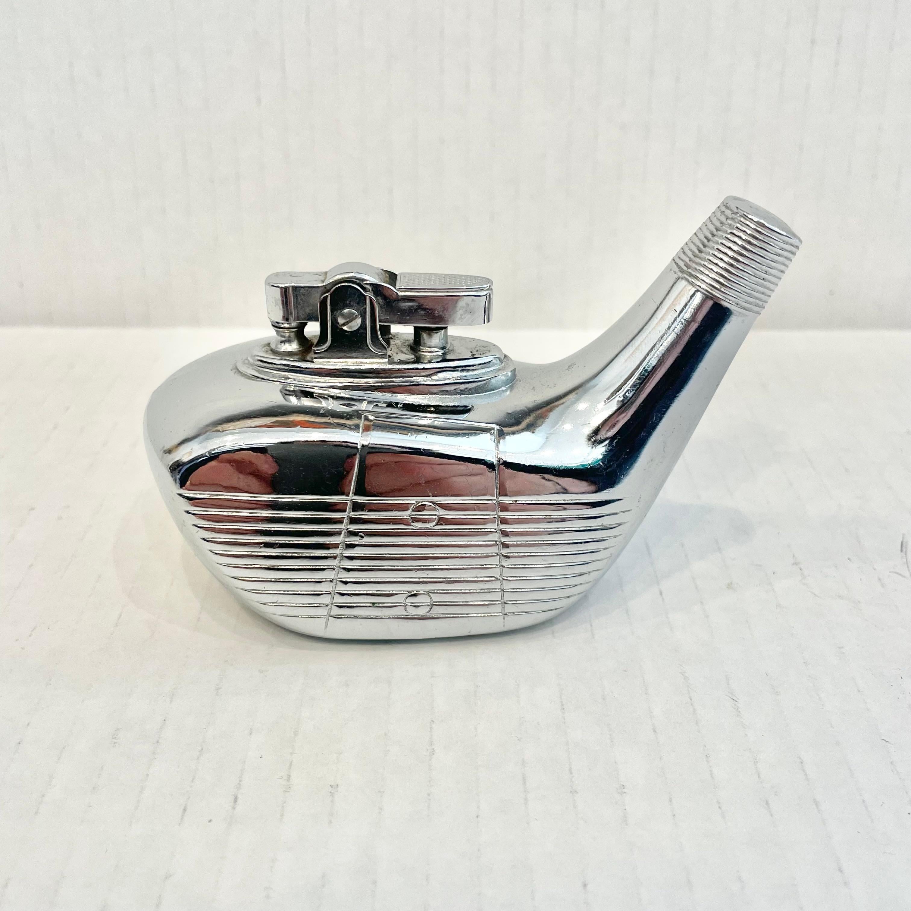 Cool vintage table lighter in the shape of a golf club driving head. Made completely of metal with a hollow body. Beautiful silver color with details like a grooved face. Cool tobacco accessory and conversation piece. Working lighter. Very unusual