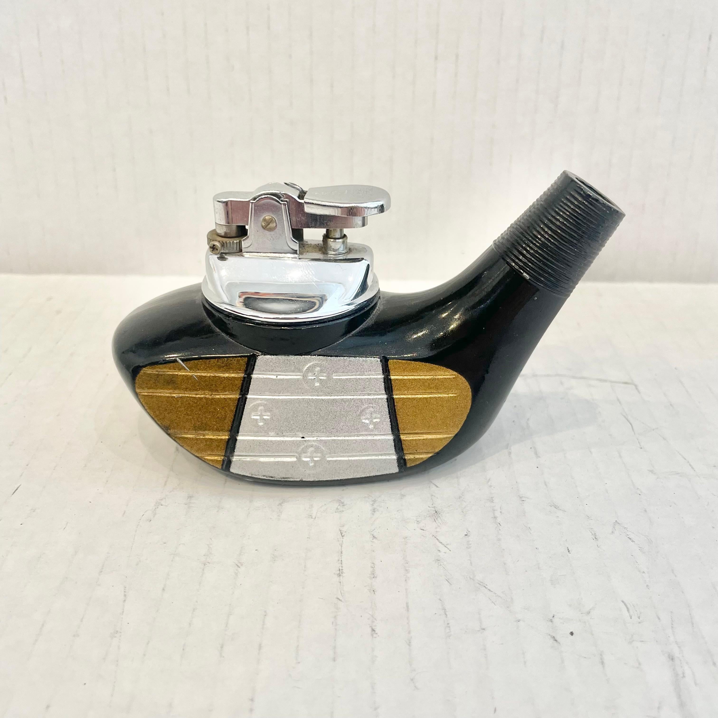 Cool vintage table lighter in the shape of a golf club driving head. Made completely of metal with a hollow body. Beautiful black body with silver and gold face plate with a grooved face. Cool tobacco accessory and conversation piece. Working